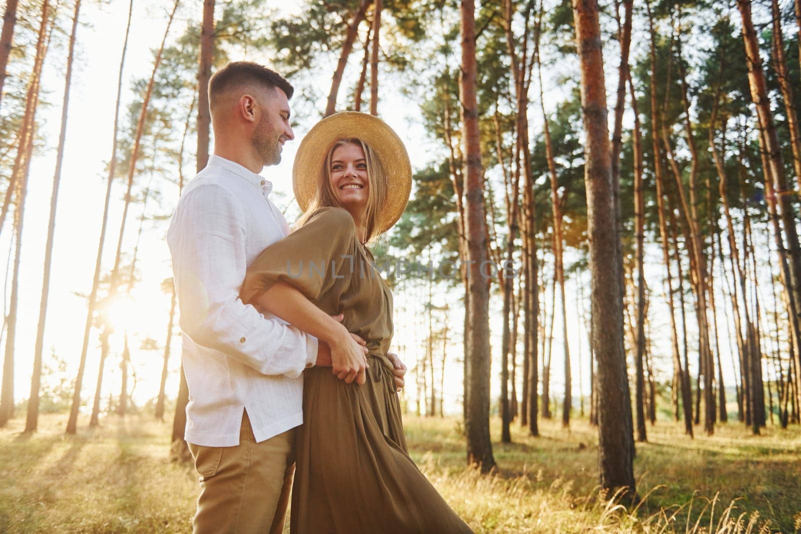 Beautiful sunlight. Happy couple is outdoors in the forest at daytime.