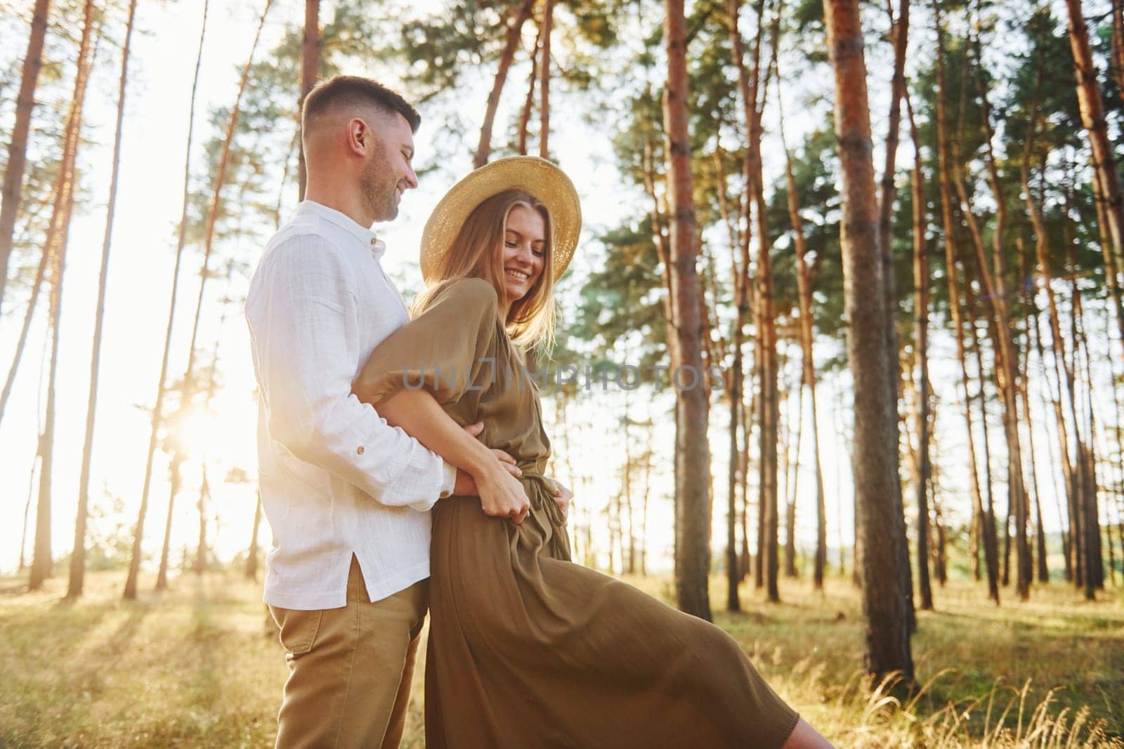 Beautiful sunlight. Happy couple is outdoors in the forest at daytime.