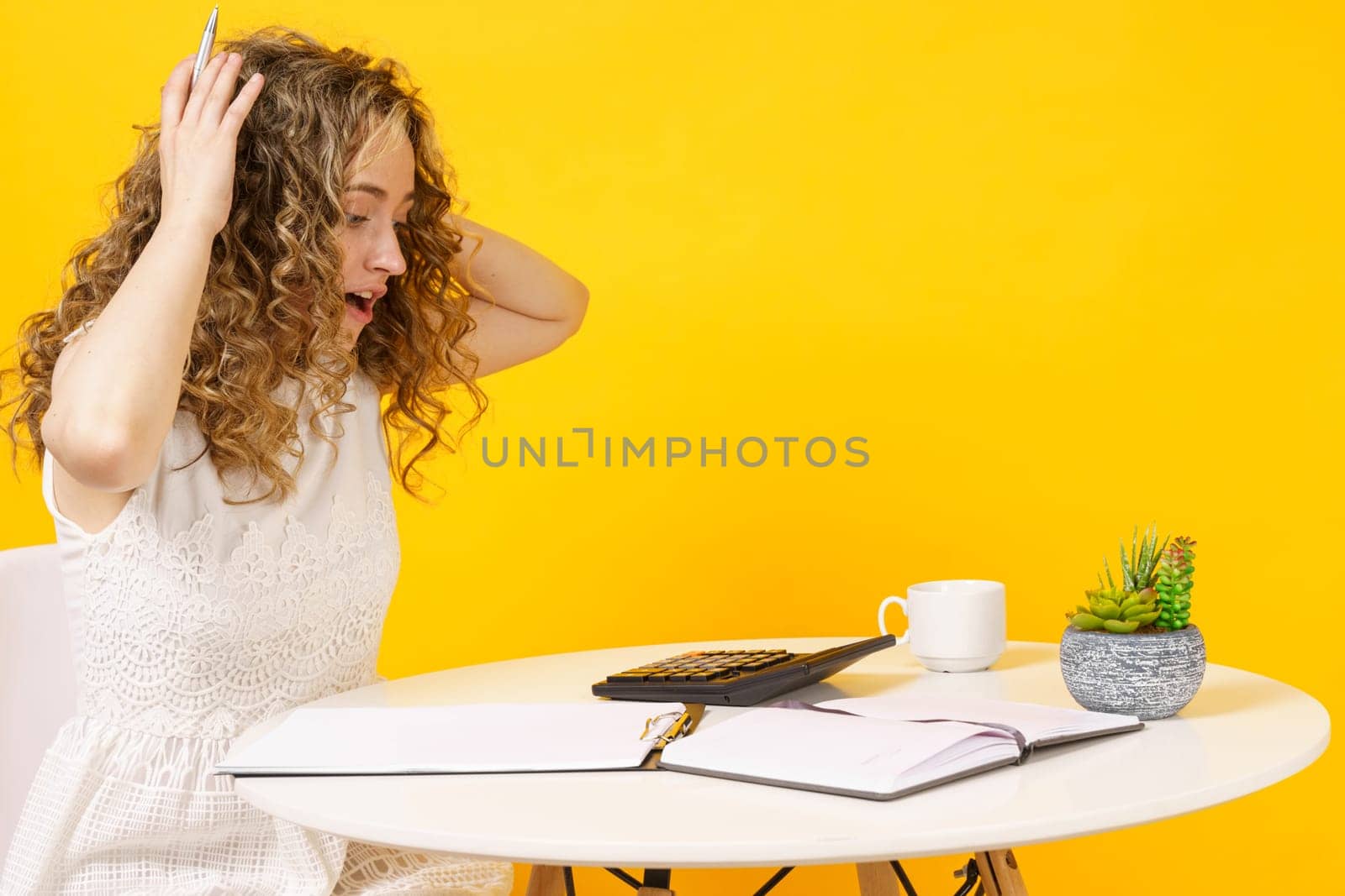 A young woman sits at a table, works with documents, considers, studies. Education. Business. Isolated on yellow background