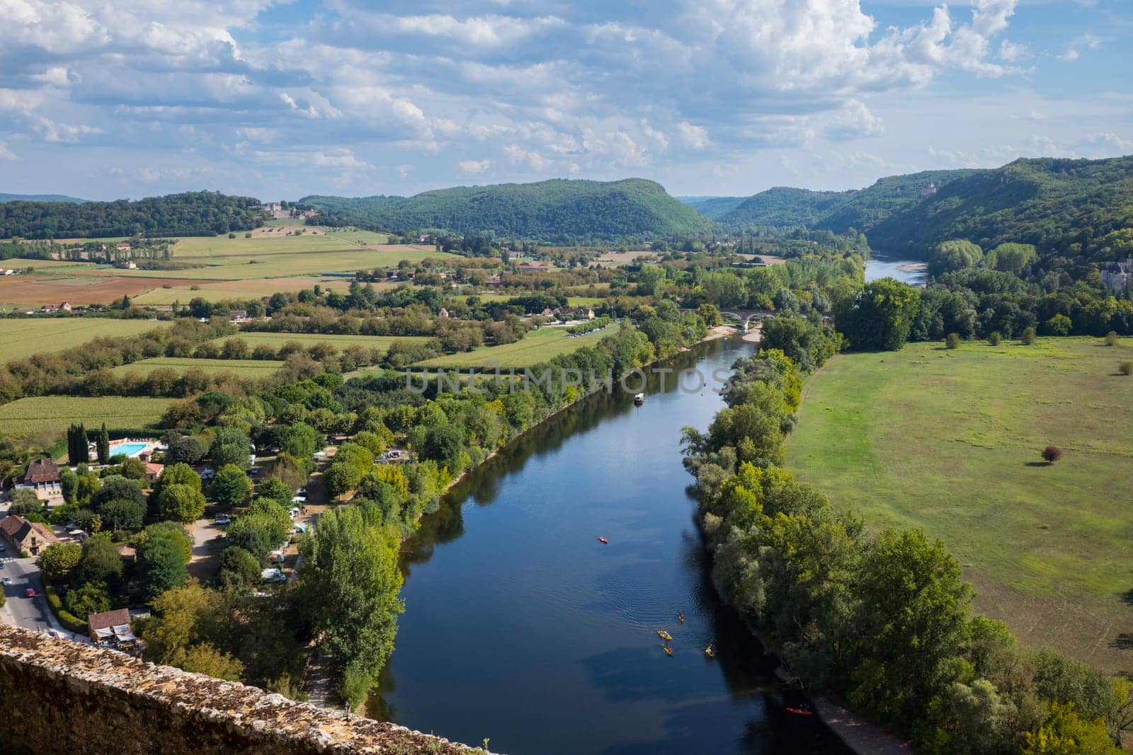 the Dordogne river with links a campsite seen from the castle of beynac with the hills and boats on the river in the background