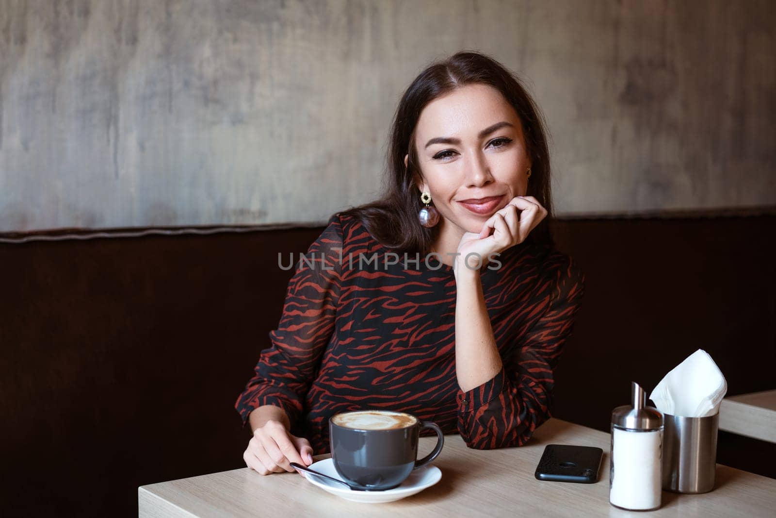 Young woman at a table in a cafe with coffee by EkaterinaPereslavtseva