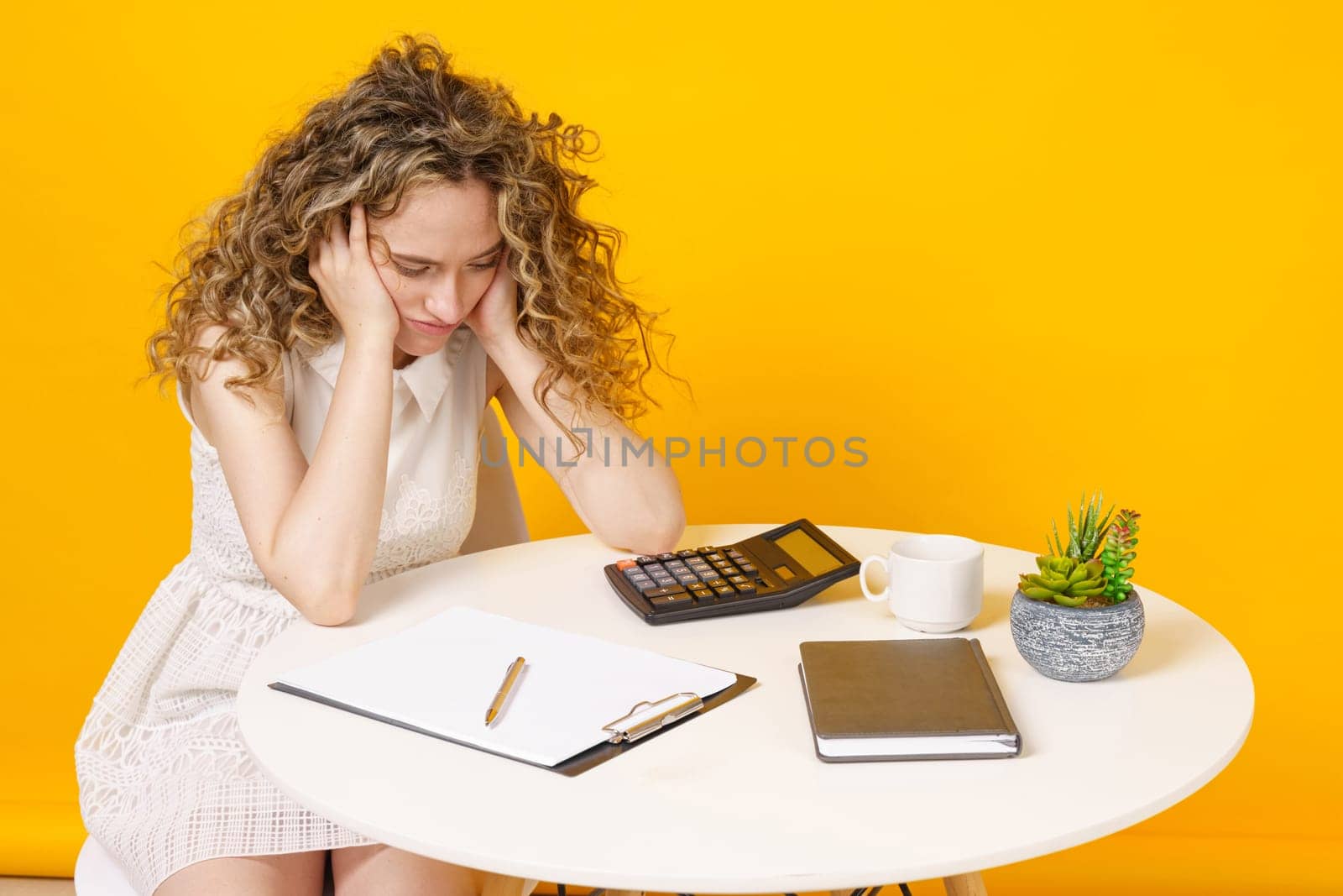 Young woman is sitting at the table, tired of office work. Education. Business.