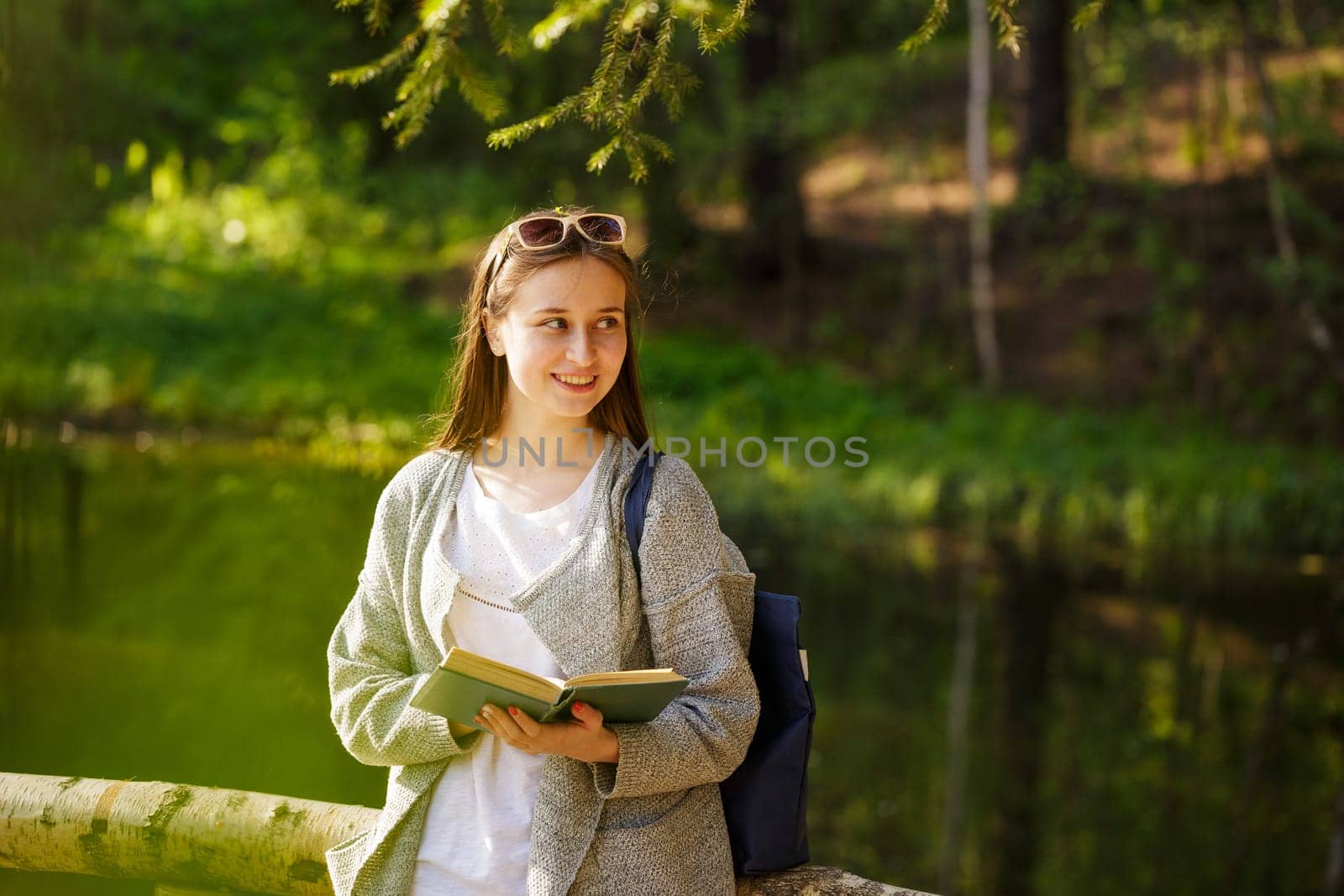 Young caucasian woman in the park reading a book on a spring sunny day,