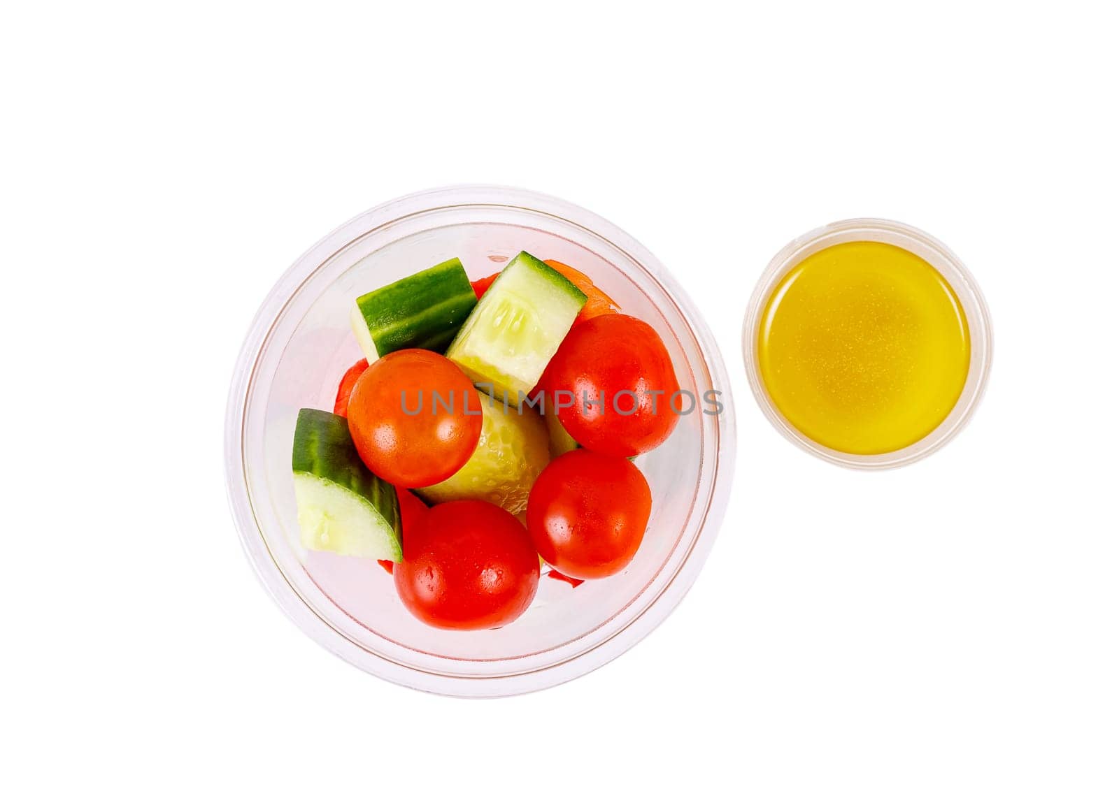 Salad of cucumbers, cherry tomatoes, peppers and dressing on a white background. Top view. Isolated