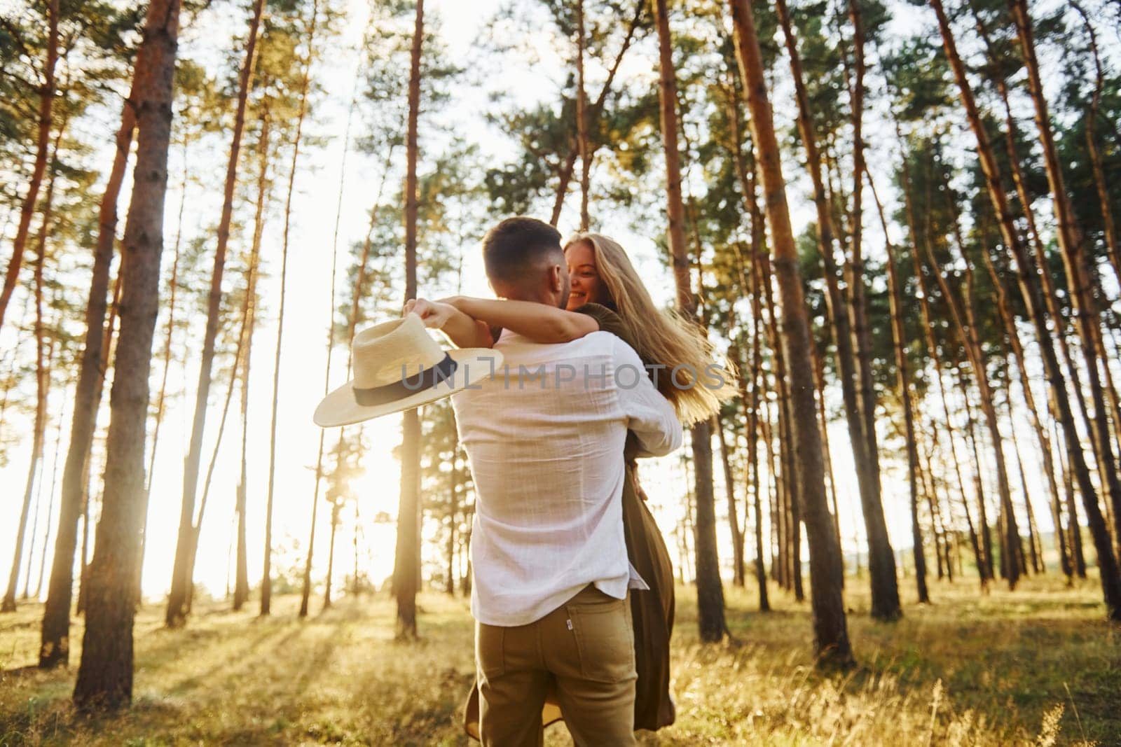 Embracing and kissing. Happy couple is outdoors in the forest at daytime.