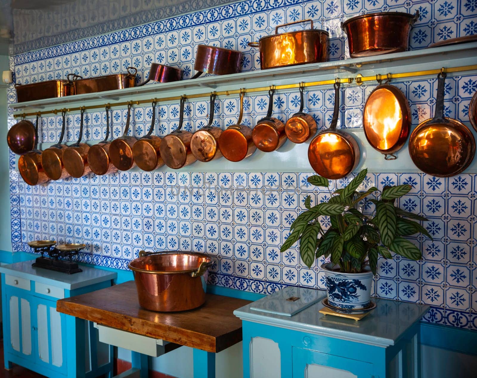 an old vintage kitchen with copper pots and pans with a blue tiled wall by compuinfoto