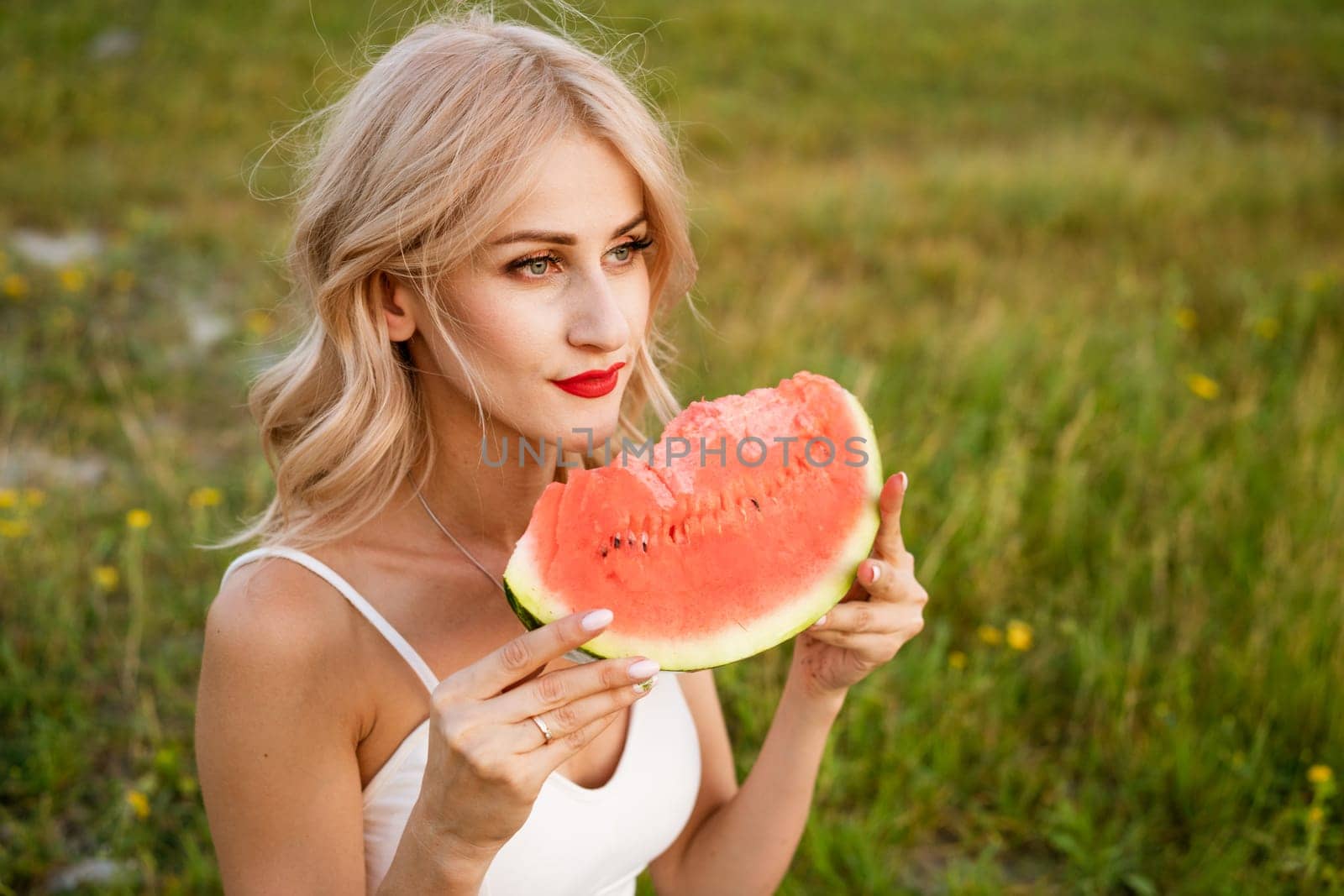 Close-up portrait of a woman biting a watermelon in nature. by EkaterinaPereslavtseva