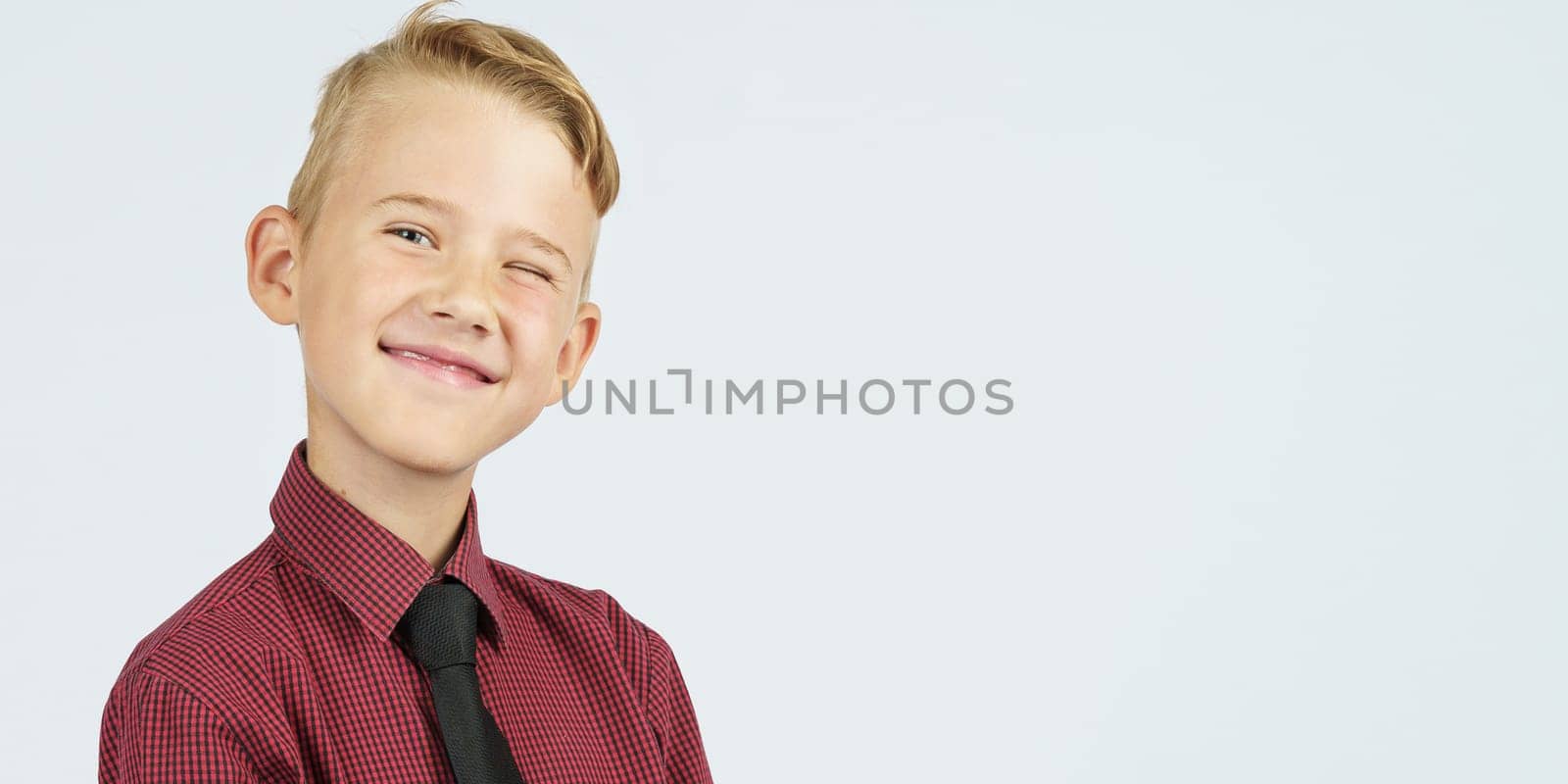 A portrait of a schoolboy who squints and smiles. Isolated background. Education concept.