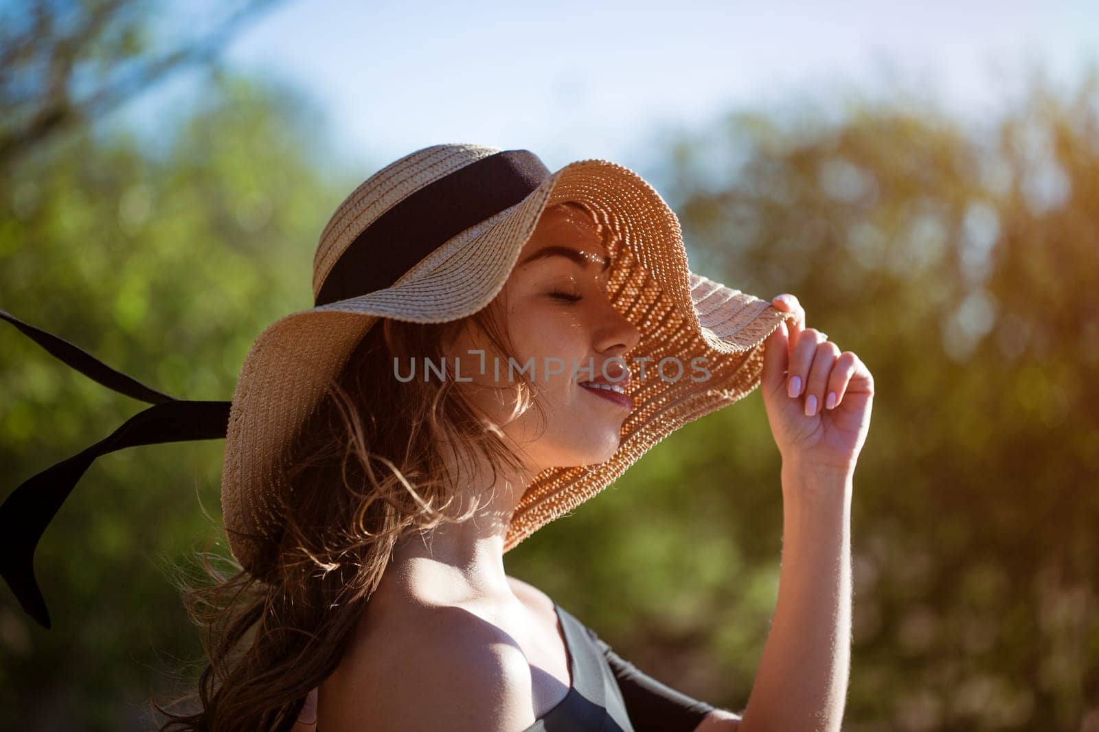 Cheerful young woman in straw sun hat smiles toothy smile close up on summer sunny day