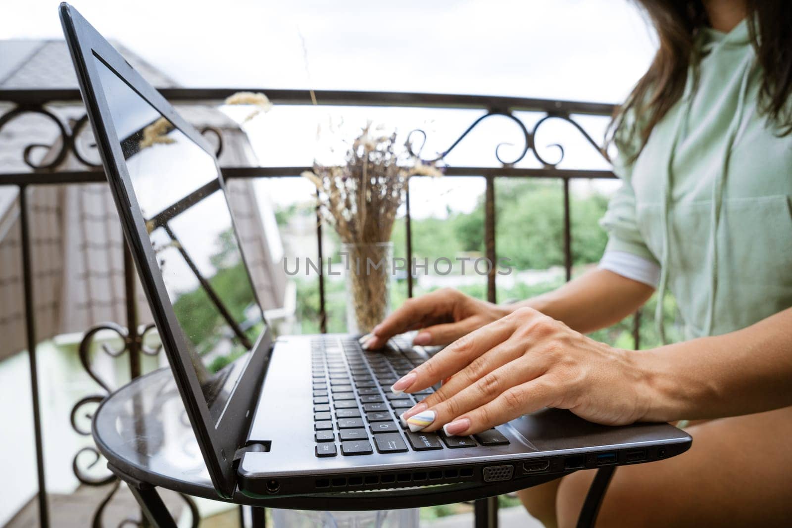 Young woman works at a laptop on the terrace. Remote work concept