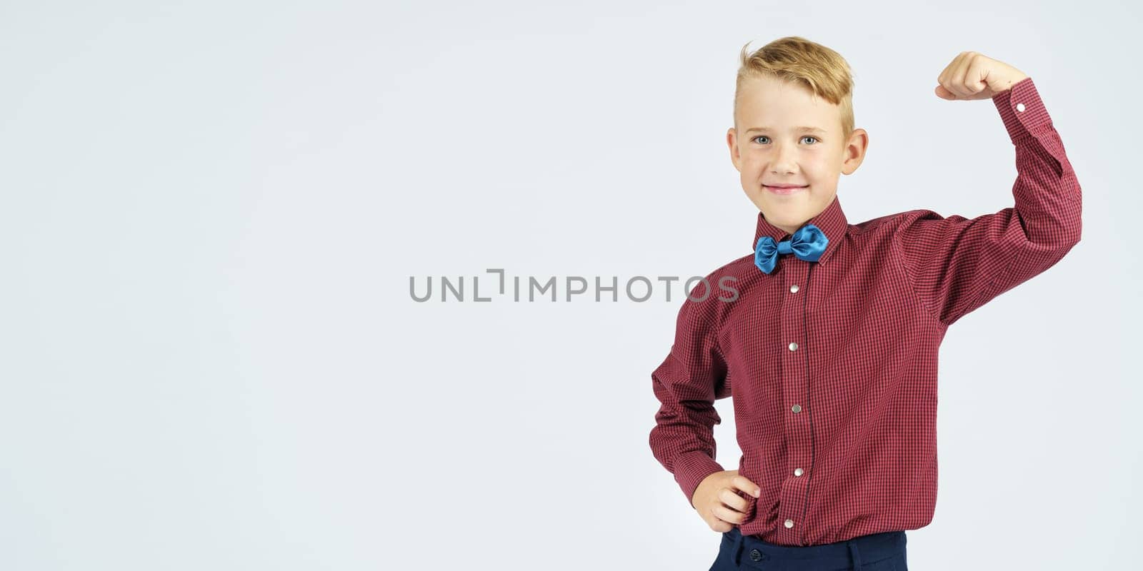 A portrait of a schoolboy who demonstrates his strength. Isolated background. Education concept.