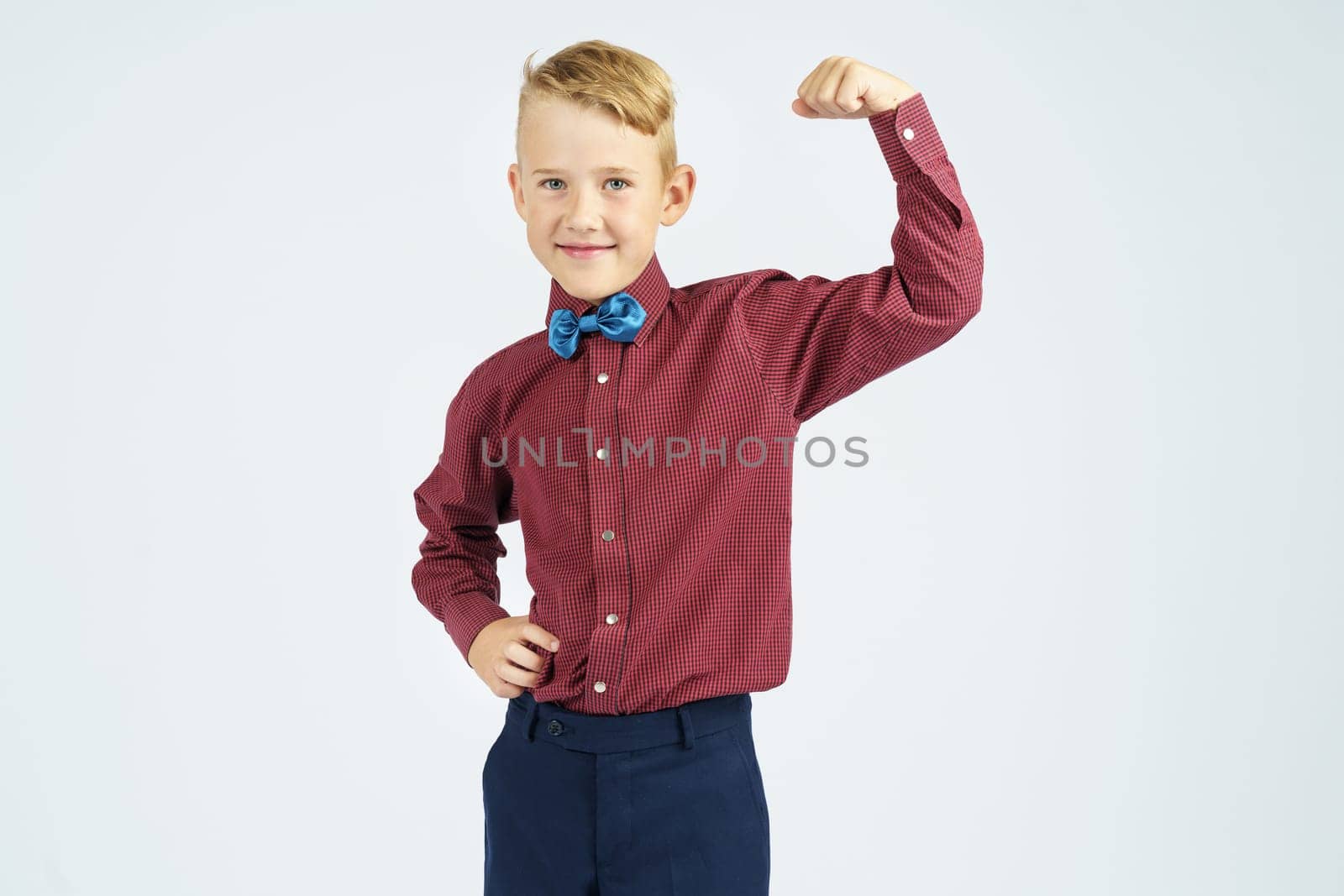 A portrait of a schoolboy who demonstrates his strength. Isolated background. Education concept.