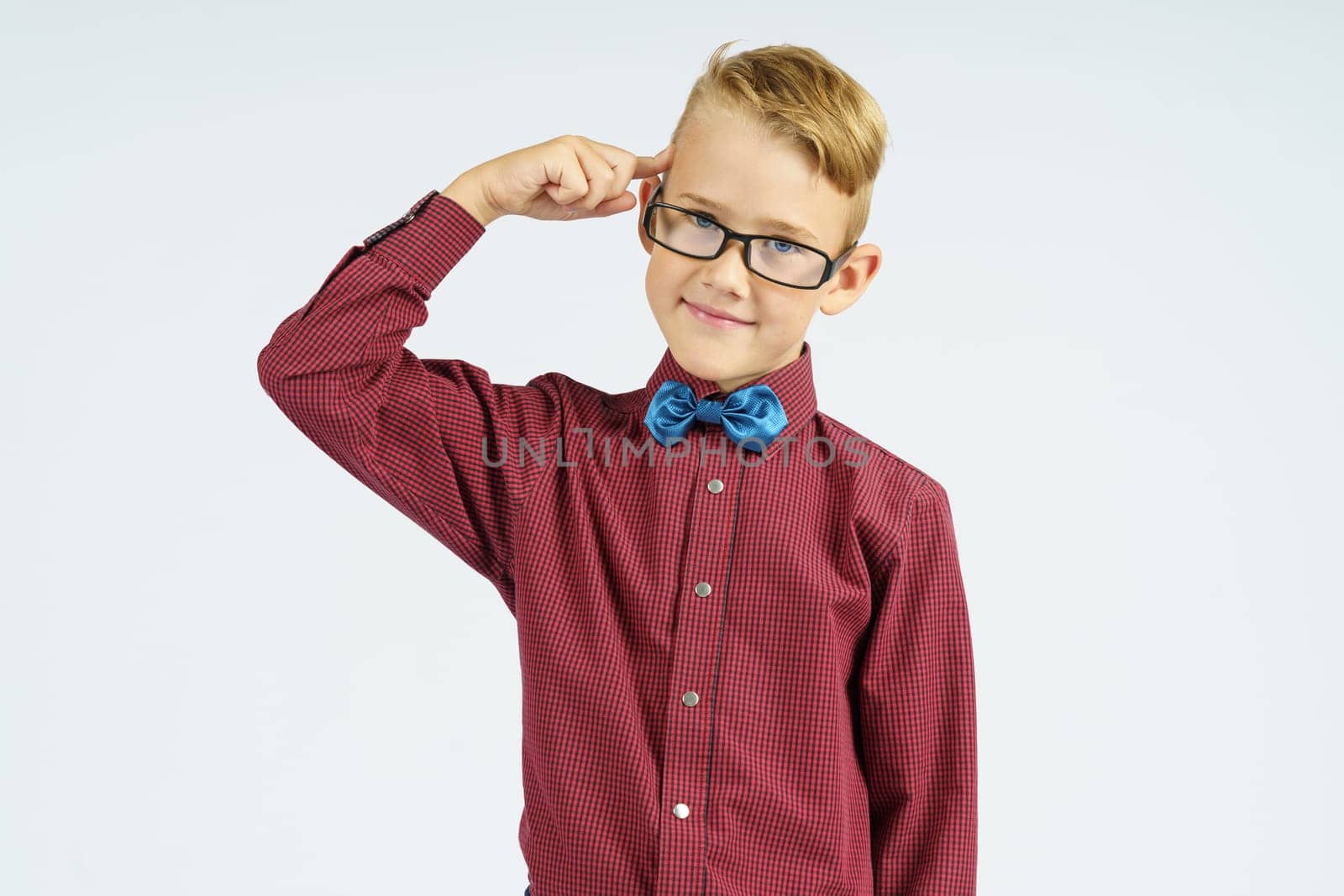 Portrait of a schoolboy in glasses who holds a finger to his temple Isolated background. Education concept.