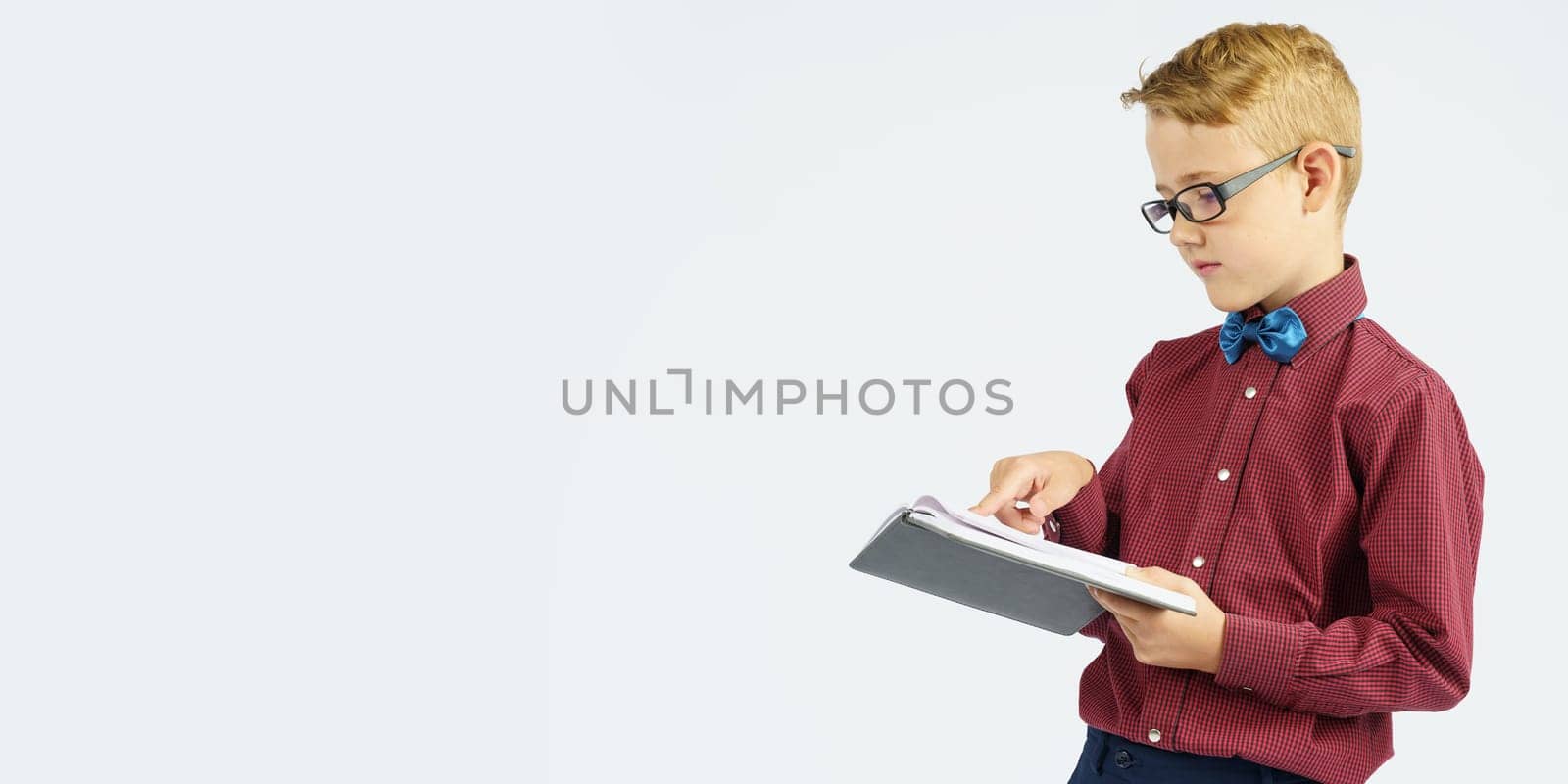 A schoolboy with glasses reads a book he holds in his hands. Isolated background. by Sd28DimoN_1976