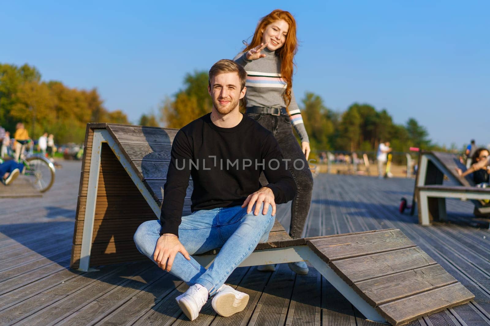 happy couple guy and girl are sitting on a wooden deck hugging by EkaterinaPereslavtseva