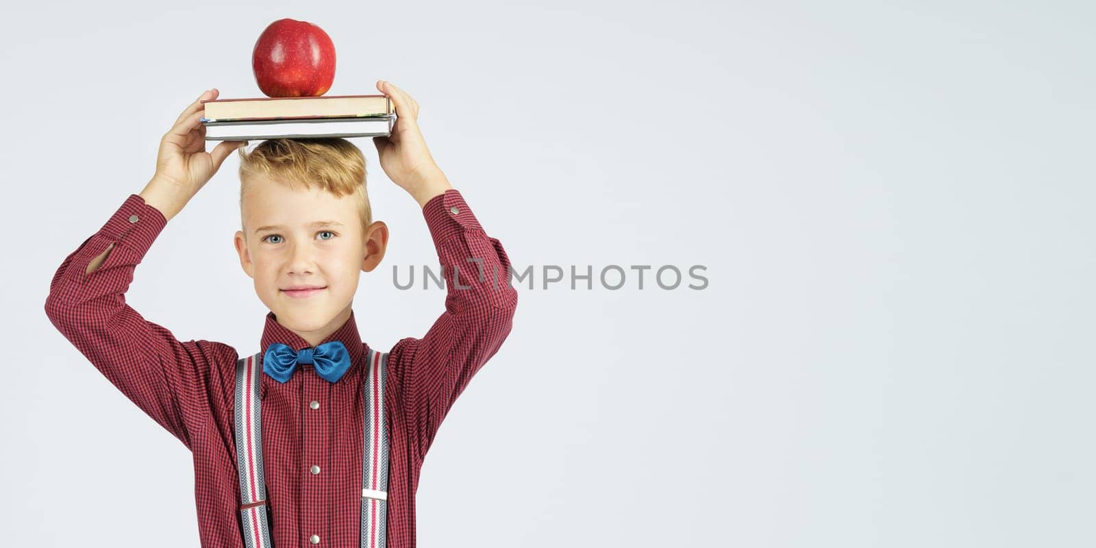 A schoolboy holds books with an apple on his head, smiles. Isolated background. by Sd28DimoN_1976