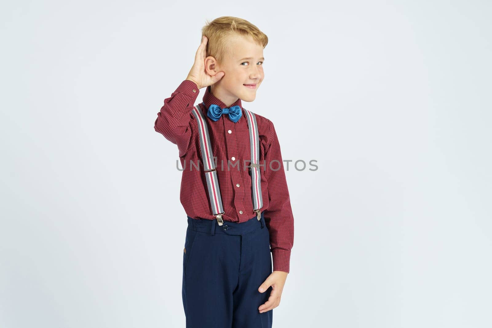 A portrait of a schoolboy who pretends to hear poorly. Isolated background. Education concept.