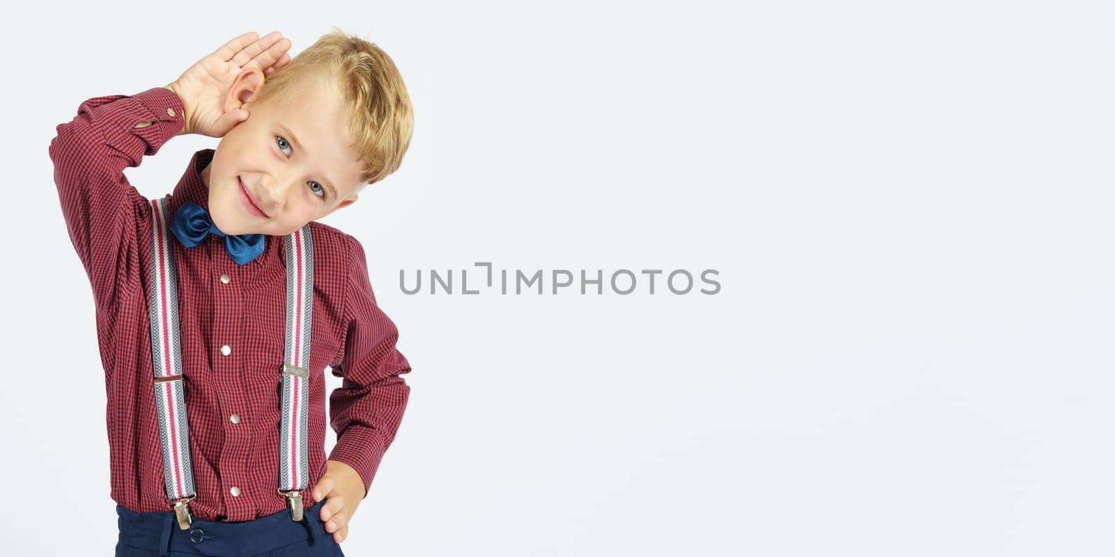 A portrait of a schoolboy who pretends to hear poorly. Isolated background. Education concept.