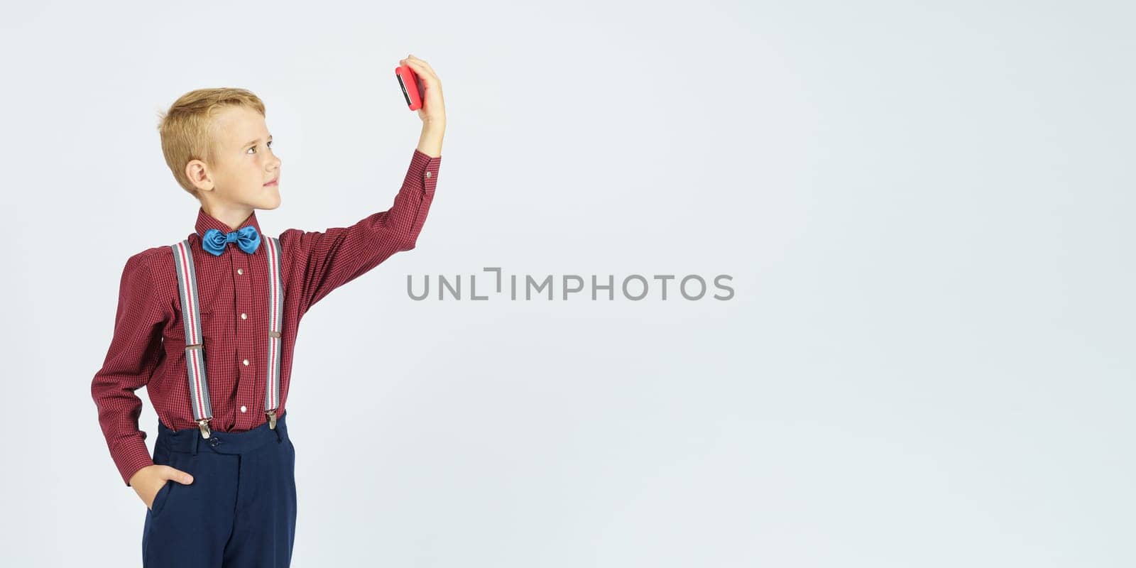 Portrait of a schoolboy taking a selfie on a mobile phone. Isolated background. Education concept.