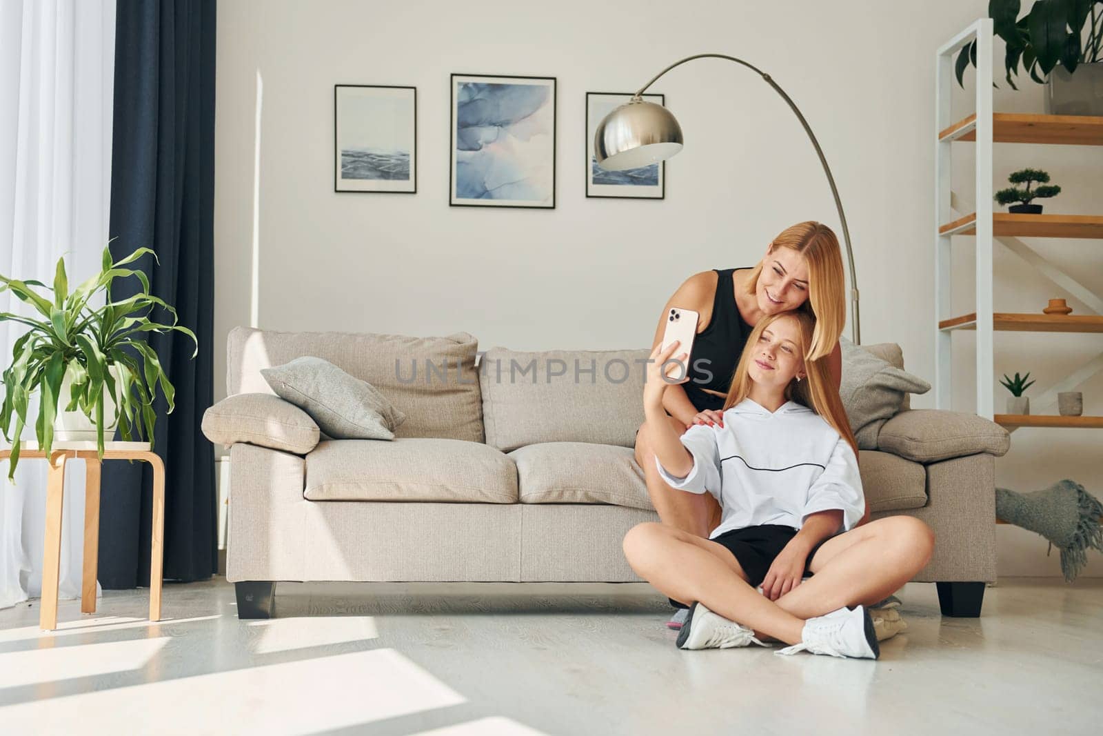 Making selfie. Female teenager with her mother is at home at daytime by Standret