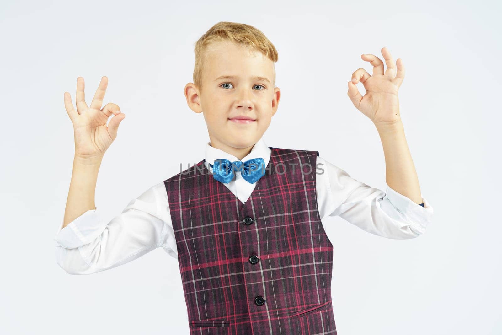 A portrait of a schoolboy who raised his hands up and makes a gesture - ok. Isolated background. Education concept.