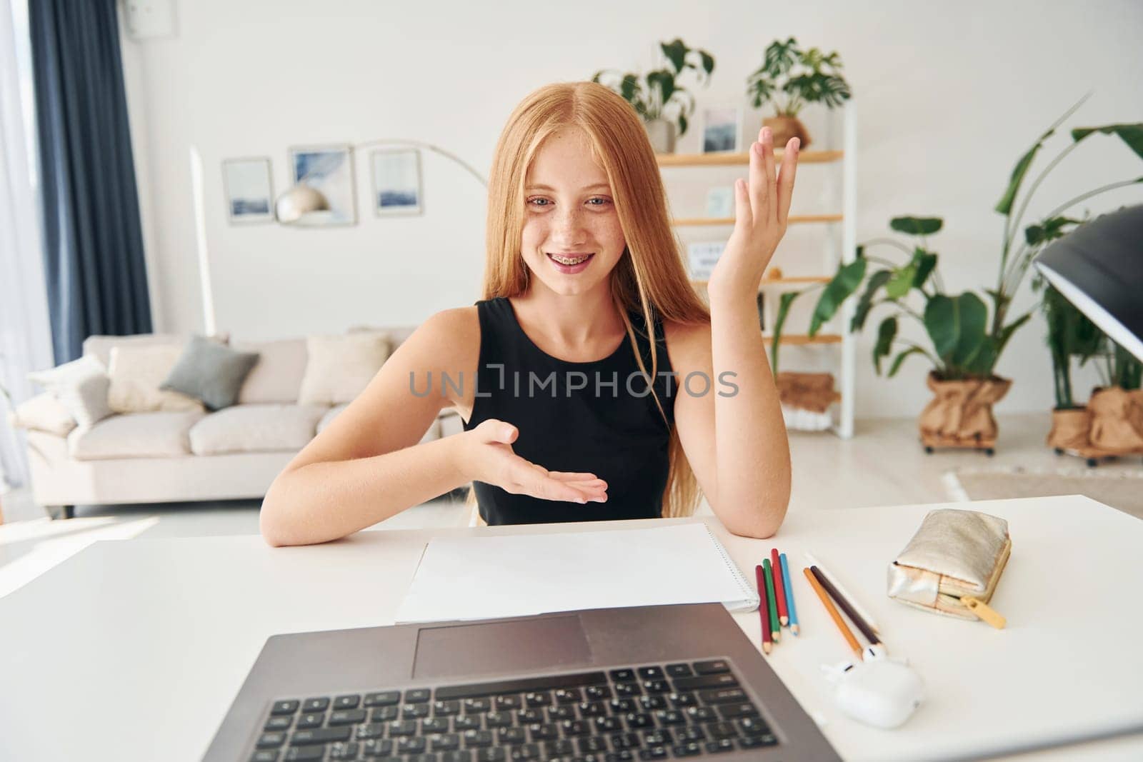 Online education. Female teenager with blonde hair is at home at daytime.