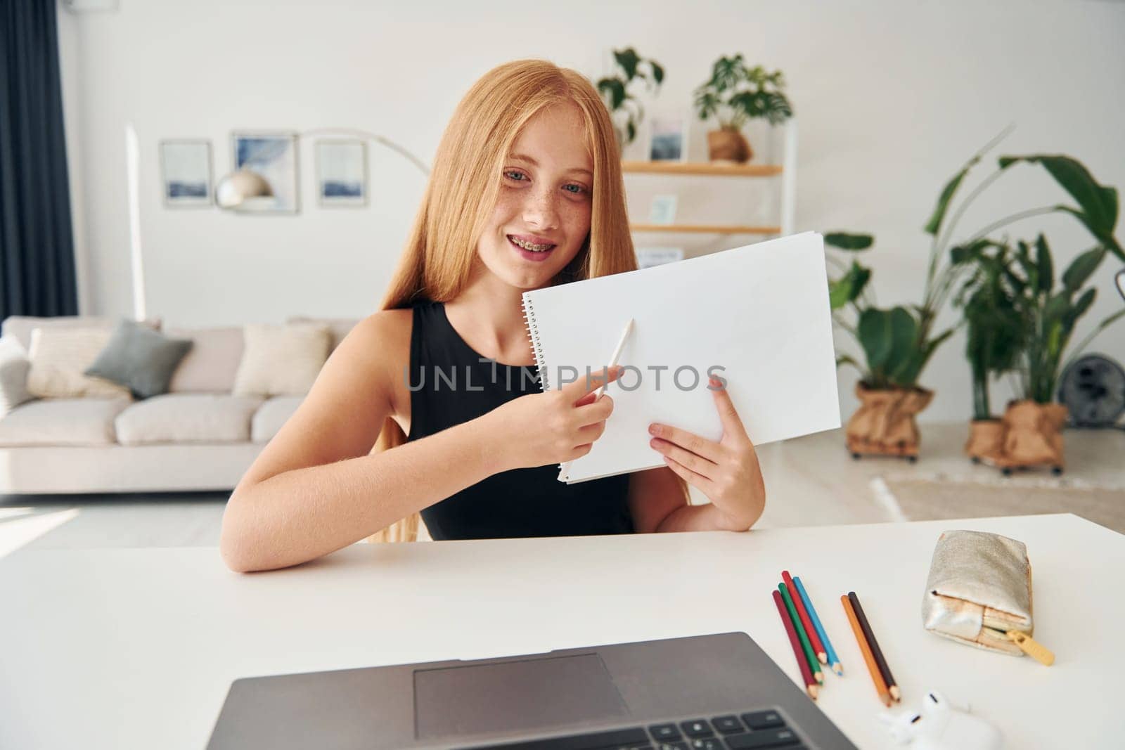 Online education. Female teenager with blonde hair is at home at daytime.