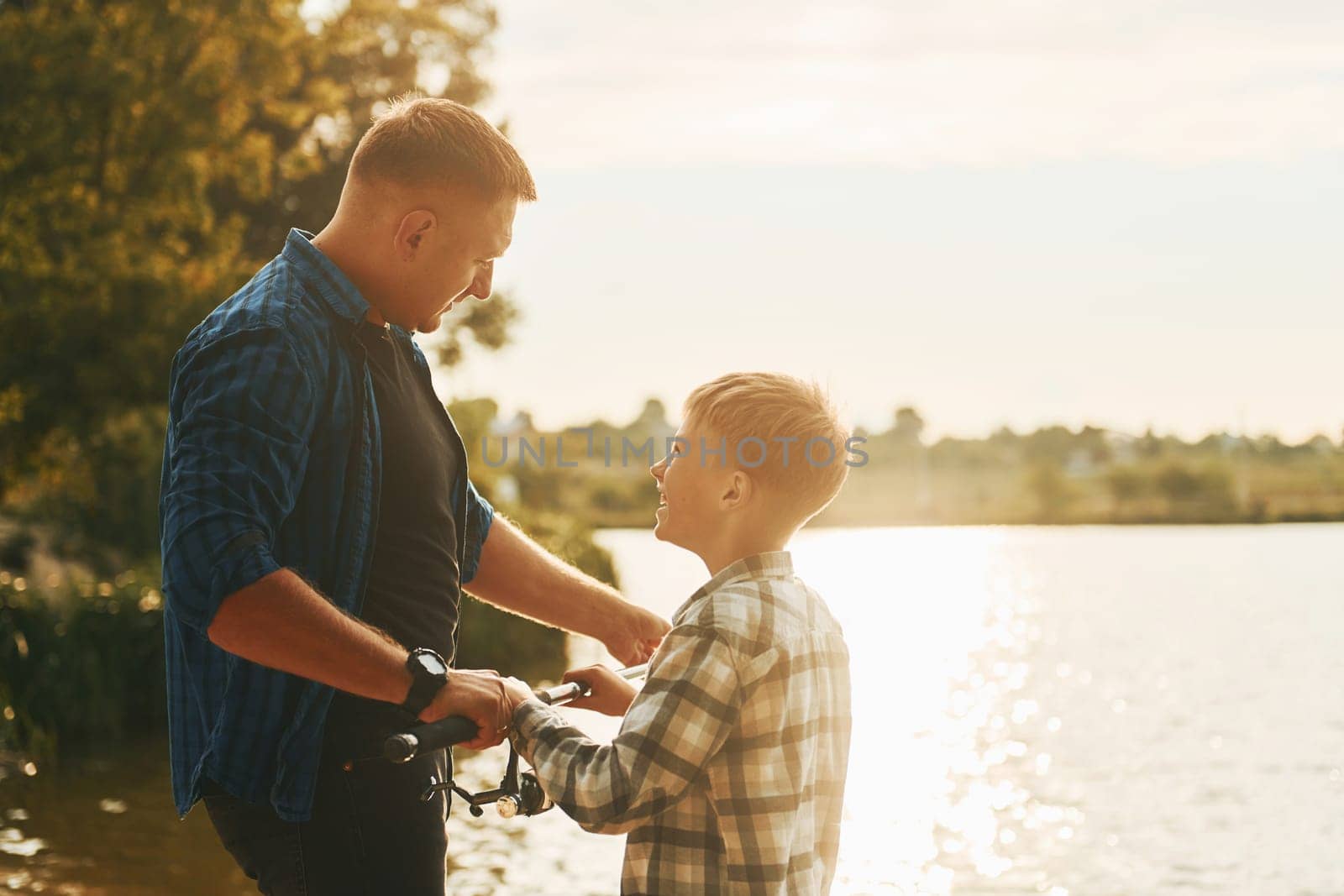 Father and son on fishing together outdoors at summertime.