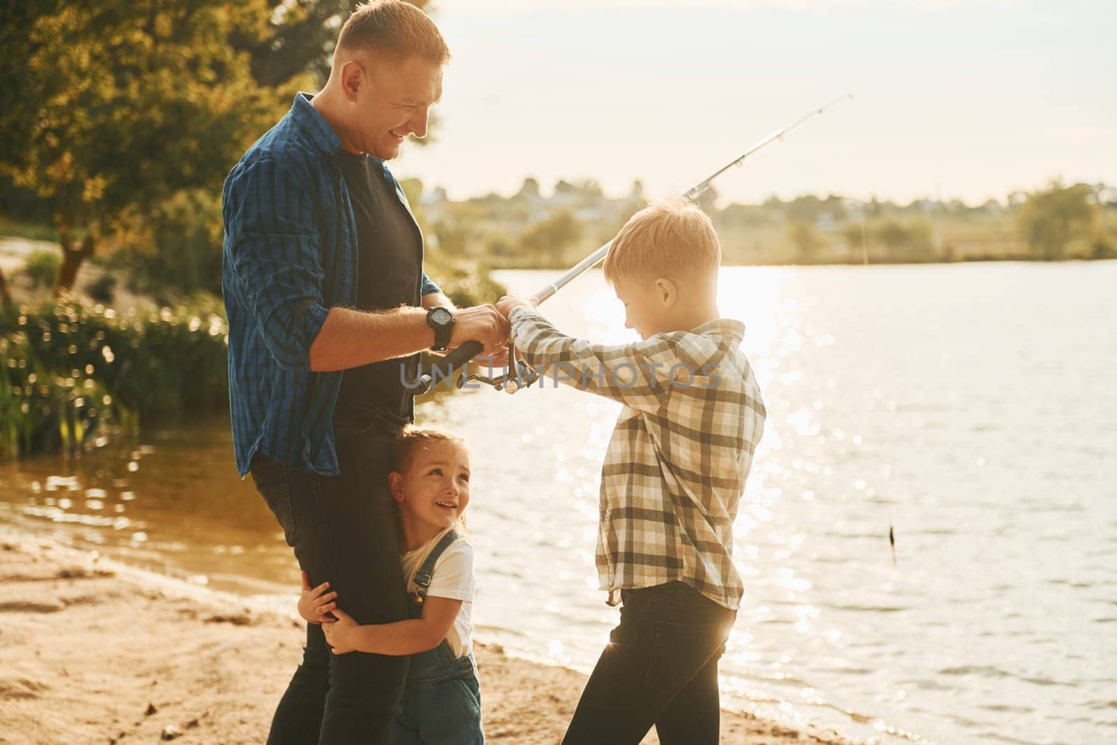 Father with son and daughter on fishing together outdoors at summertime by Standret