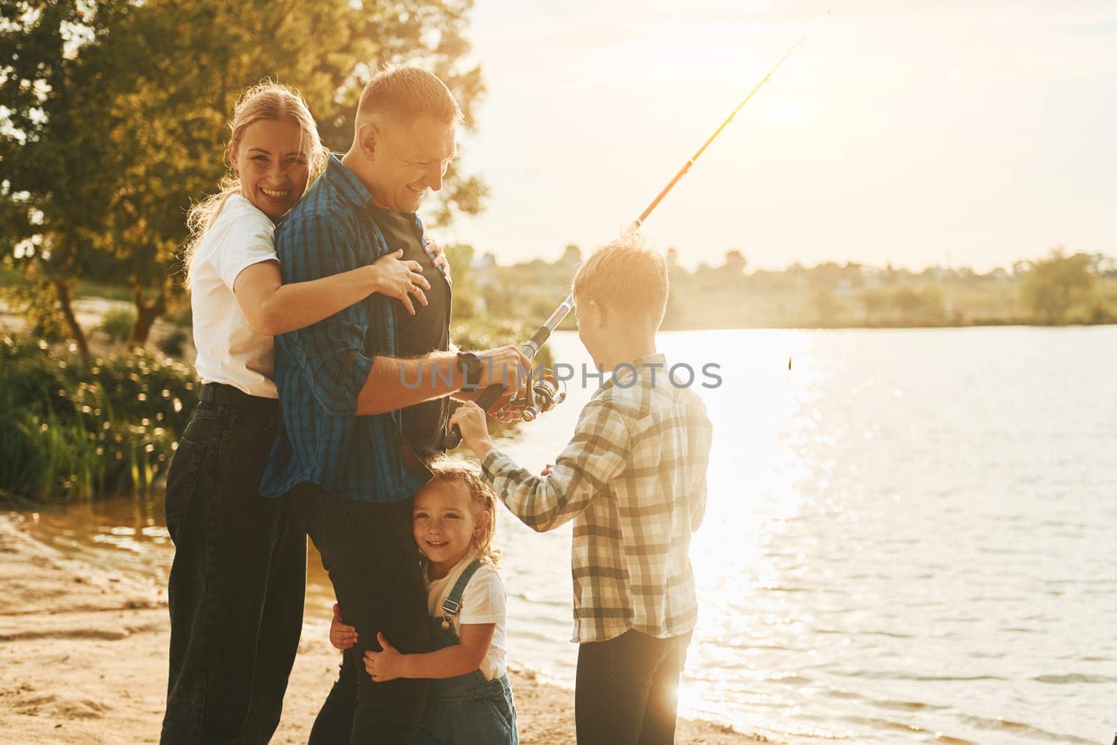 Conception of vacation. Father and mother with son and daughter on fishing together outdoors at summertime by Standret