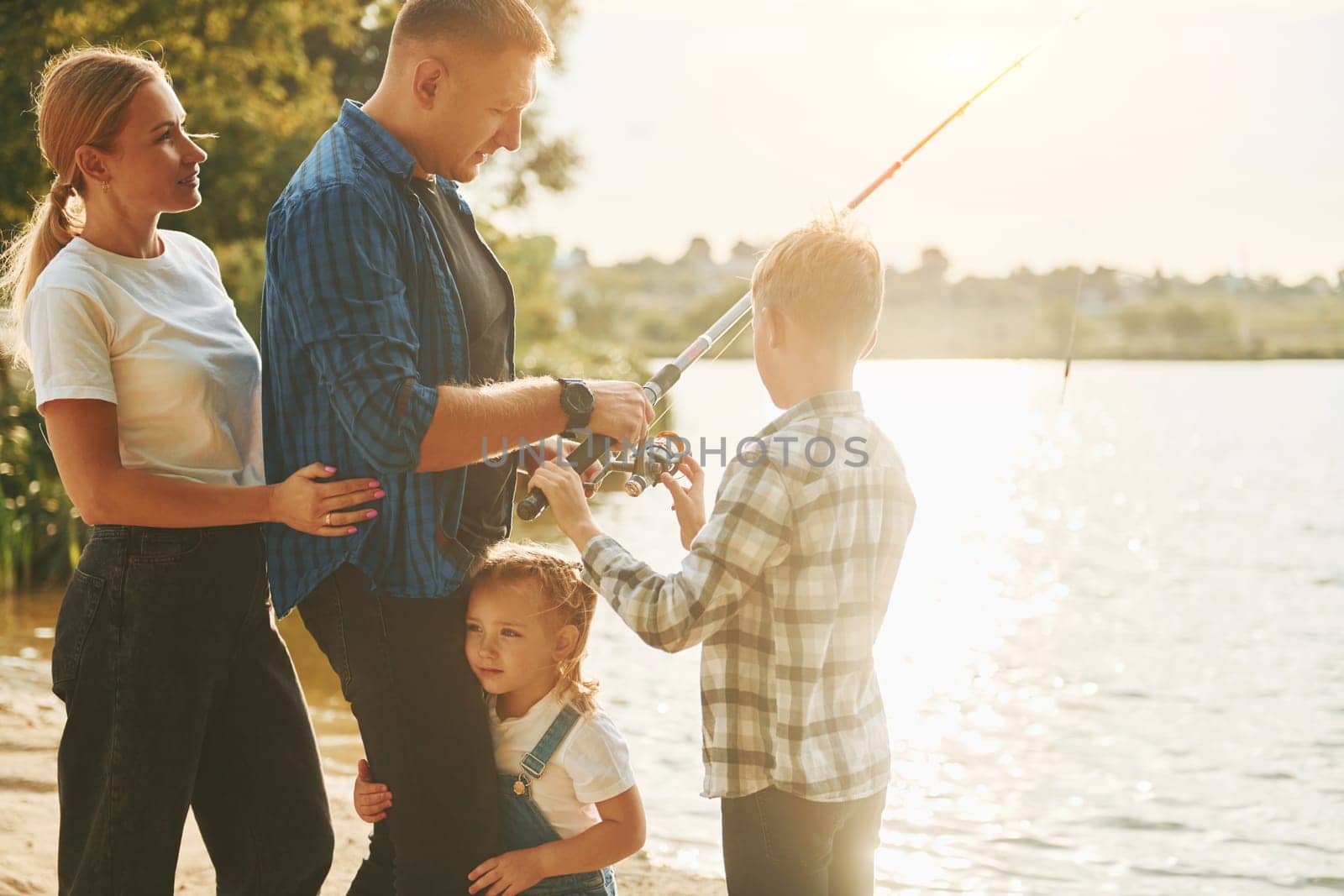 Conception of vacation. Father and mother with son and daughter on fishing together outdoors at summertime by Standret