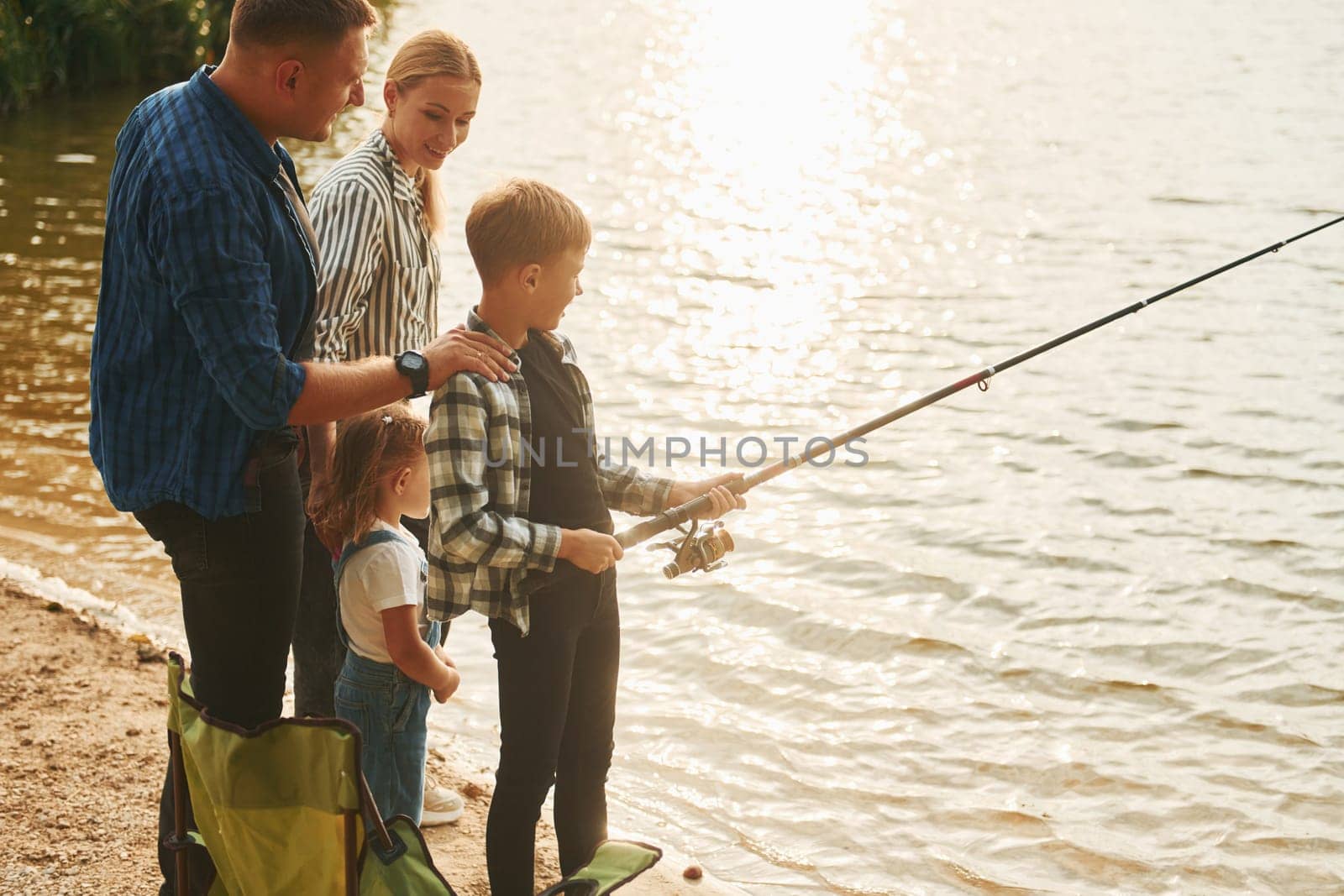 Conception of vacation. Father and mother with son and daughter on fishing together outdoors at summertime by Standret