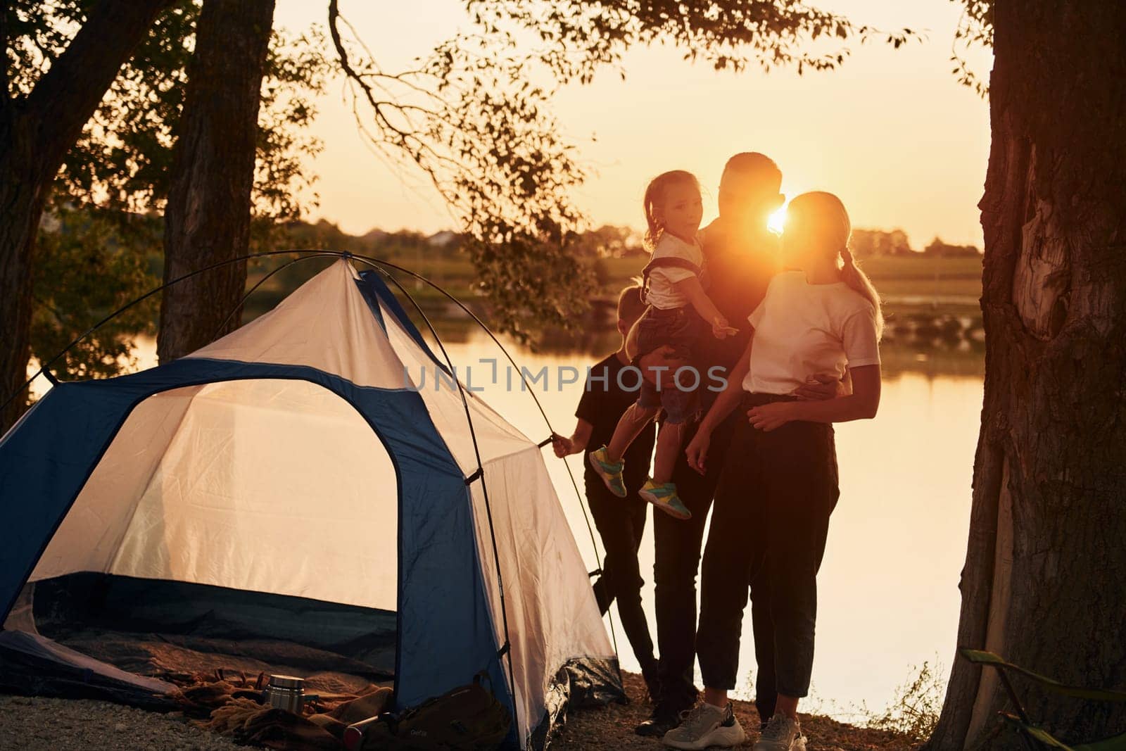 Evening time. Family of mother, father and kids is on the camping by Standret