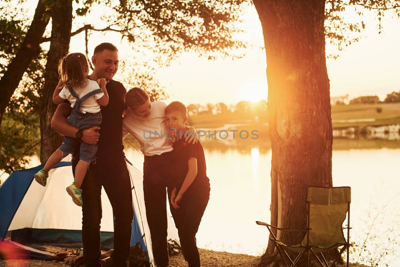 Evening time. Family of mother, father and kids is on the camping.