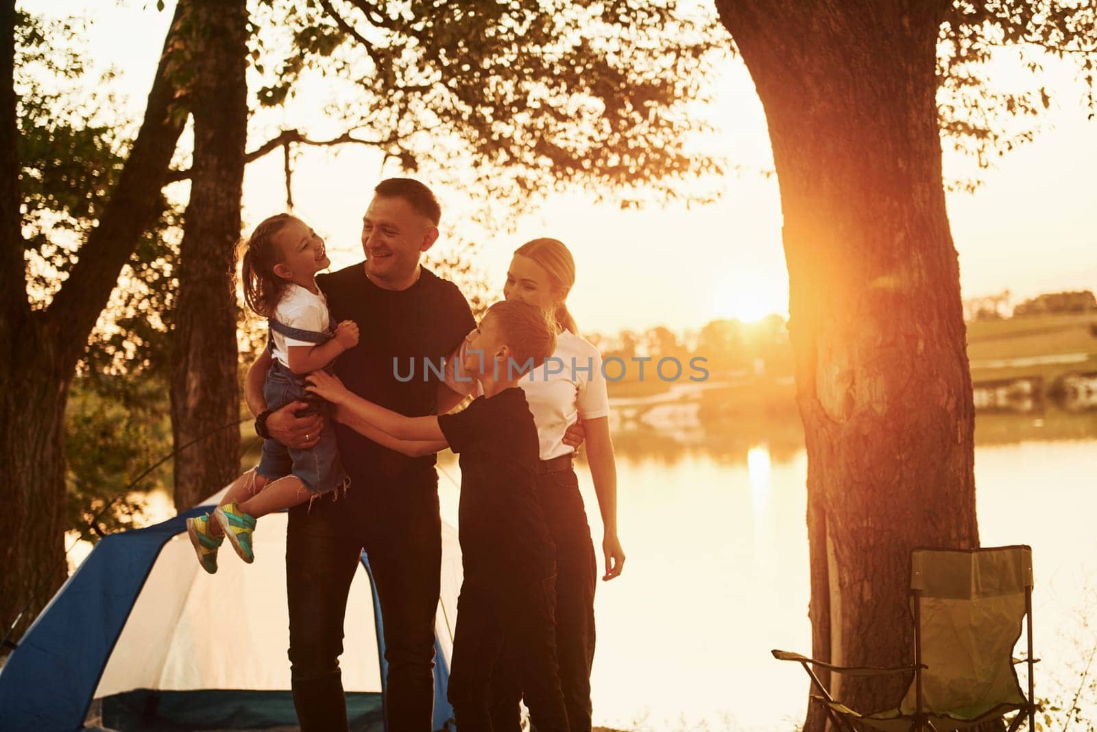 Evening time. Family of mother, father and kids is on the camping.