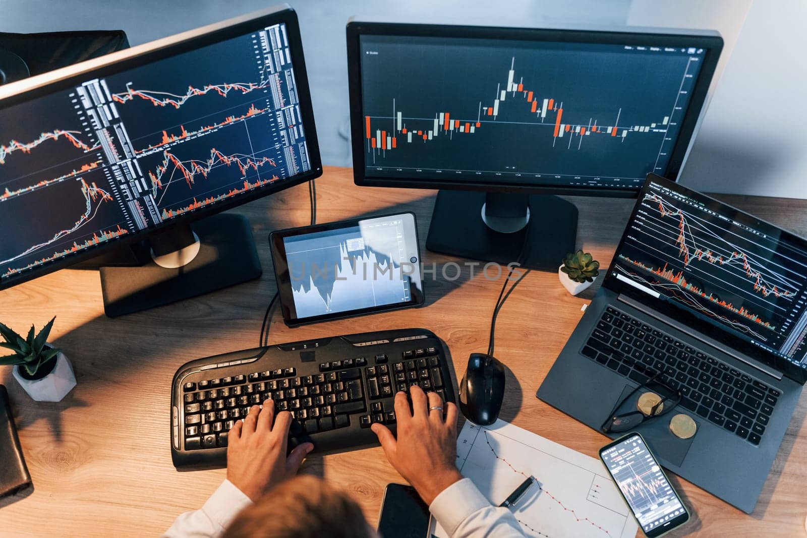 International business. Young man in formal clothes is in office with multiple screens.