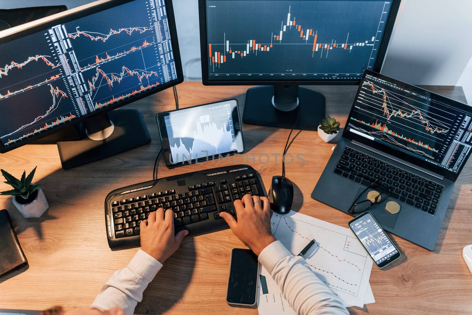 International business. Young man in formal clothes is in office with multiple screens.