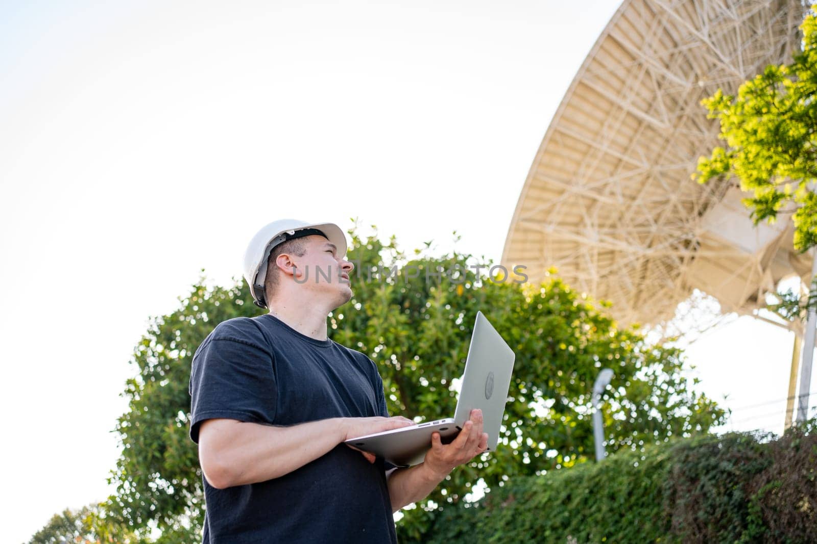 Engineer testing earth based astronomical radio telescope use laptop. Radio telescopes used in science for space observation and distant objects exploring. Big satellite dishes