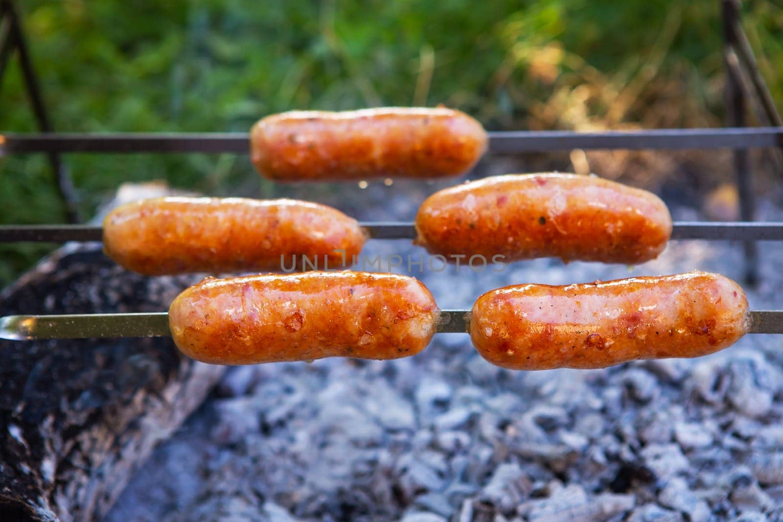 Fried sausages on skewers. Summer evenings near the fire, good weekend. Close-up. by sfinks