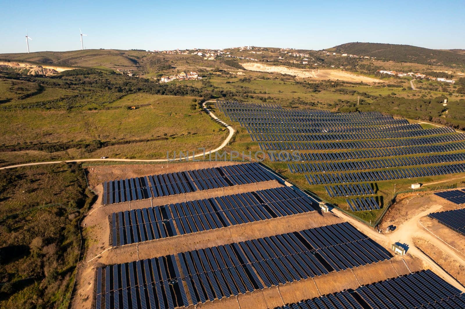 Long rows of photovoltaic panels at solar farm for converting energy of sun to electricity in concept of renewable energy and natural resources. Aerial view