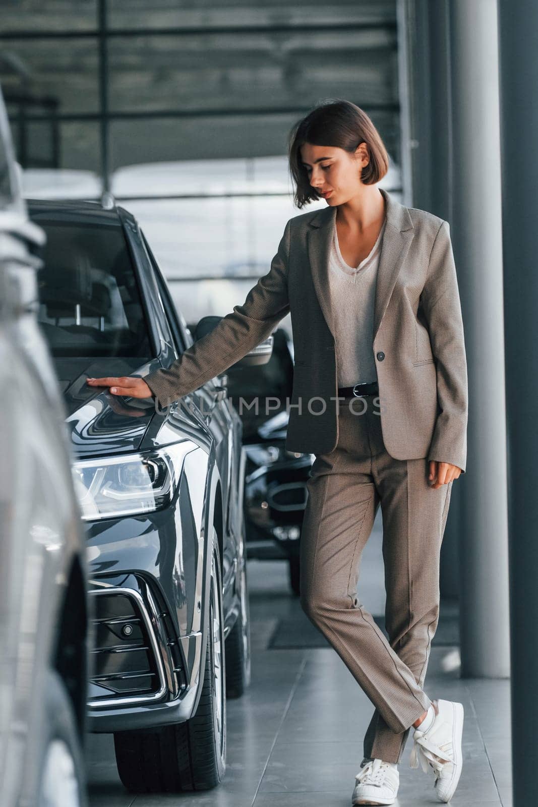 Modern technology. Woman is indoors near brand new automobile indoors.