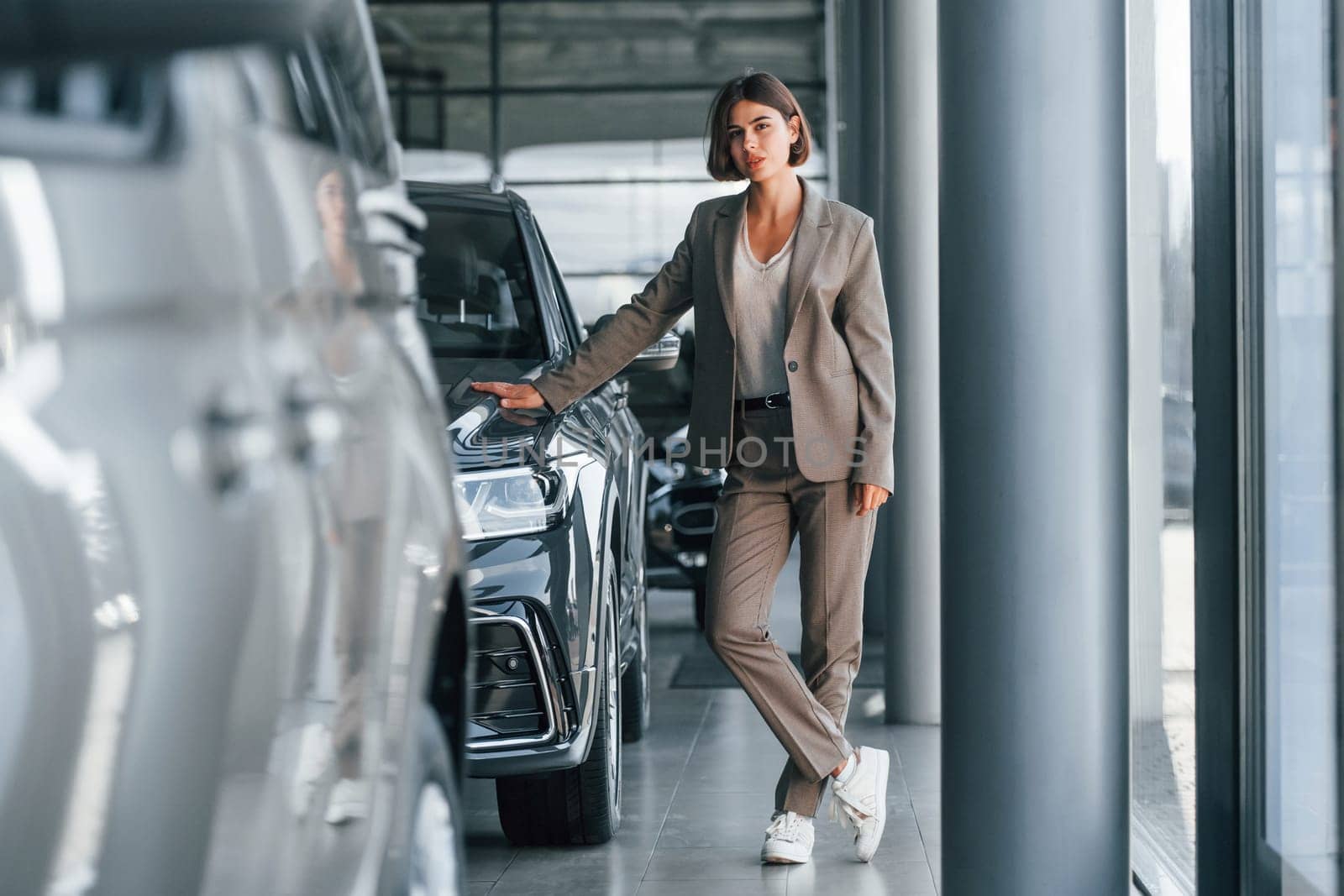 Modern technology. Woman is indoors near brand new automobile indoors.