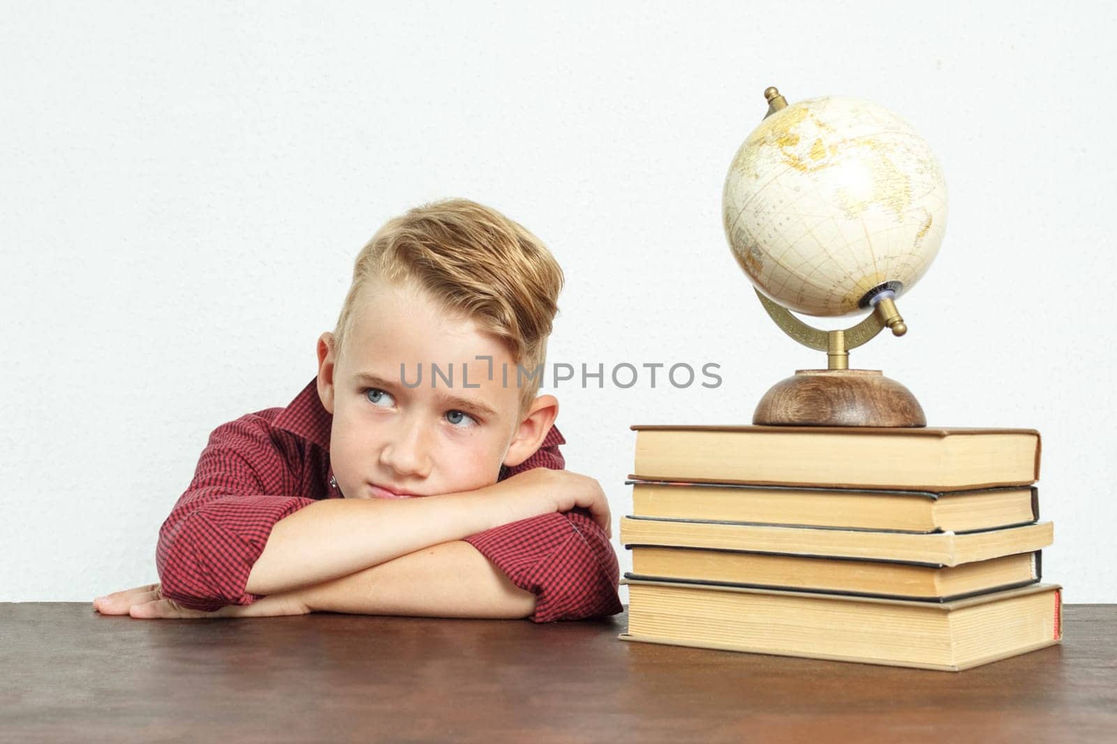 A tired schoolboy sits at the table, put his head on his hands. On the table there are books, a globe and an alarm clock. by Sd28DimoN_1976