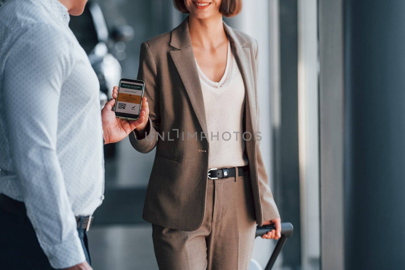 Using smartphone. Woman showing her vaccine passport to the man.