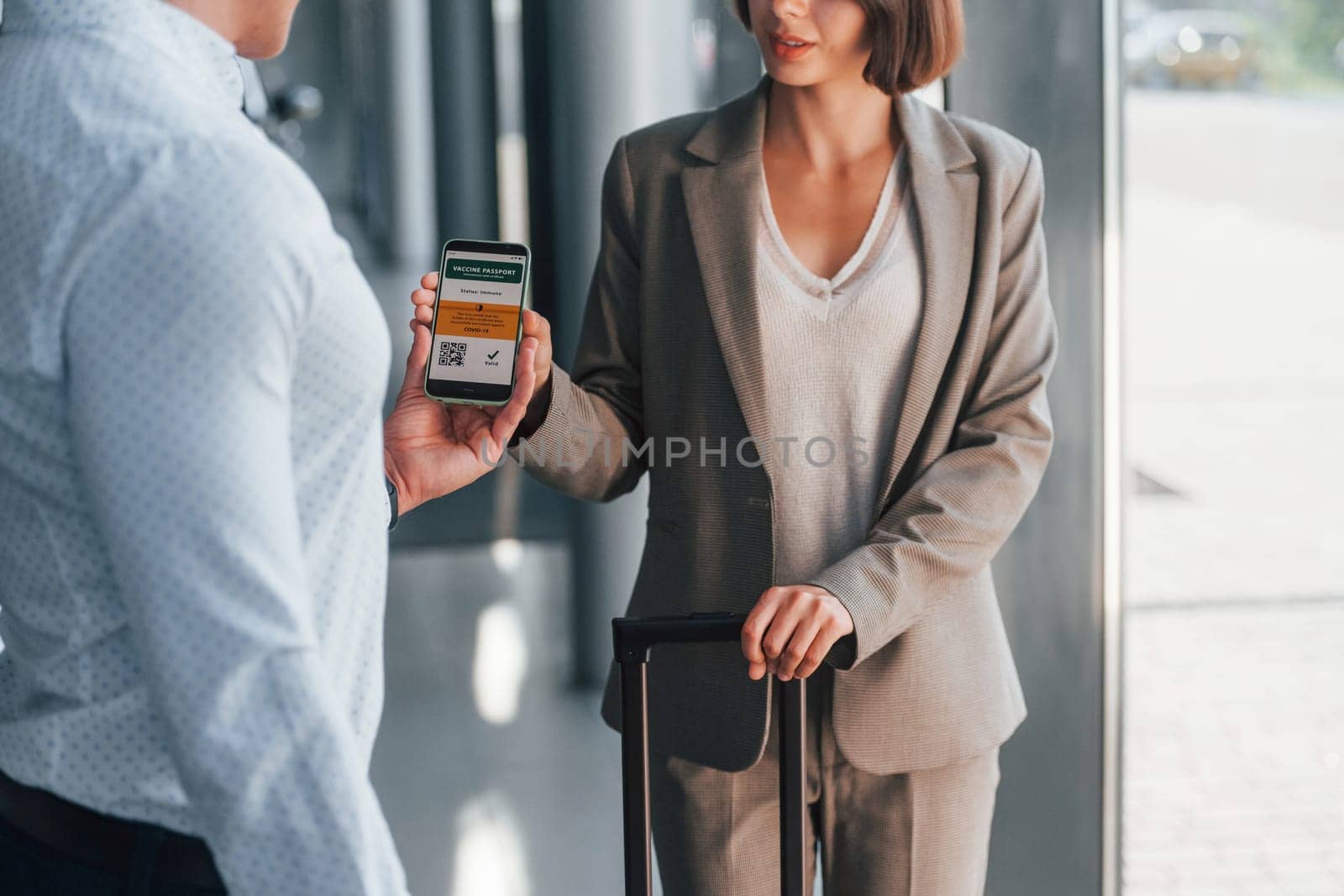 Modern technologies. Woman showing her vaccine passport by using smartphone to the man.