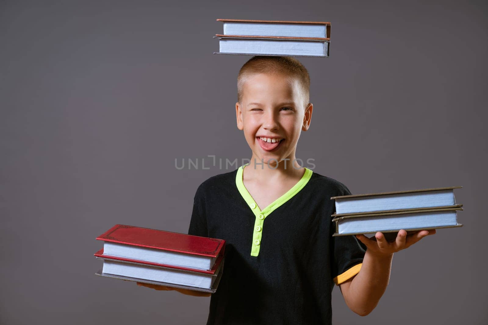 little boy hold the stacks of books in your hands and on your head by EkaterinaPereslavtseva