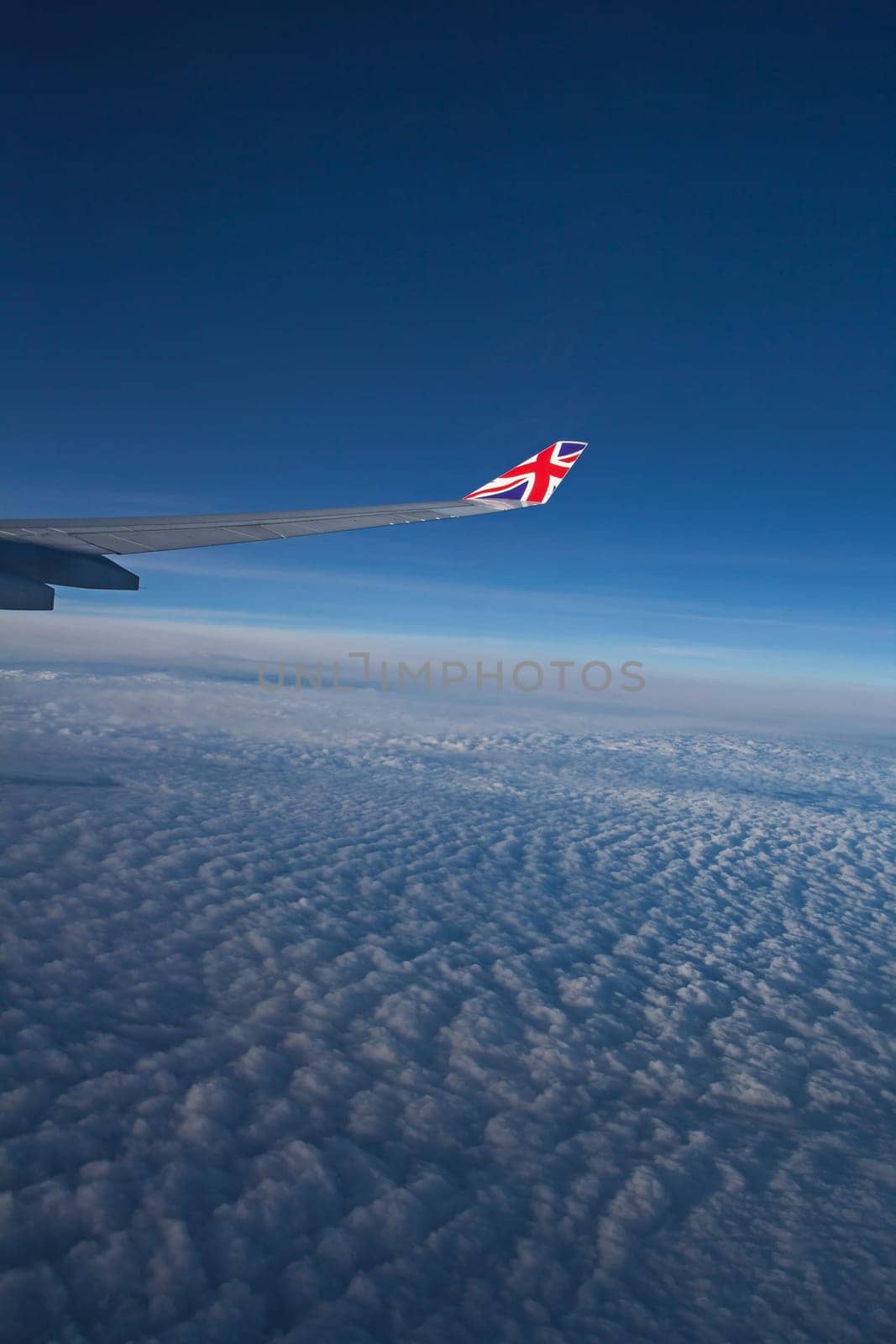 View from the porthole. Aircraft wing over cloudy skies.