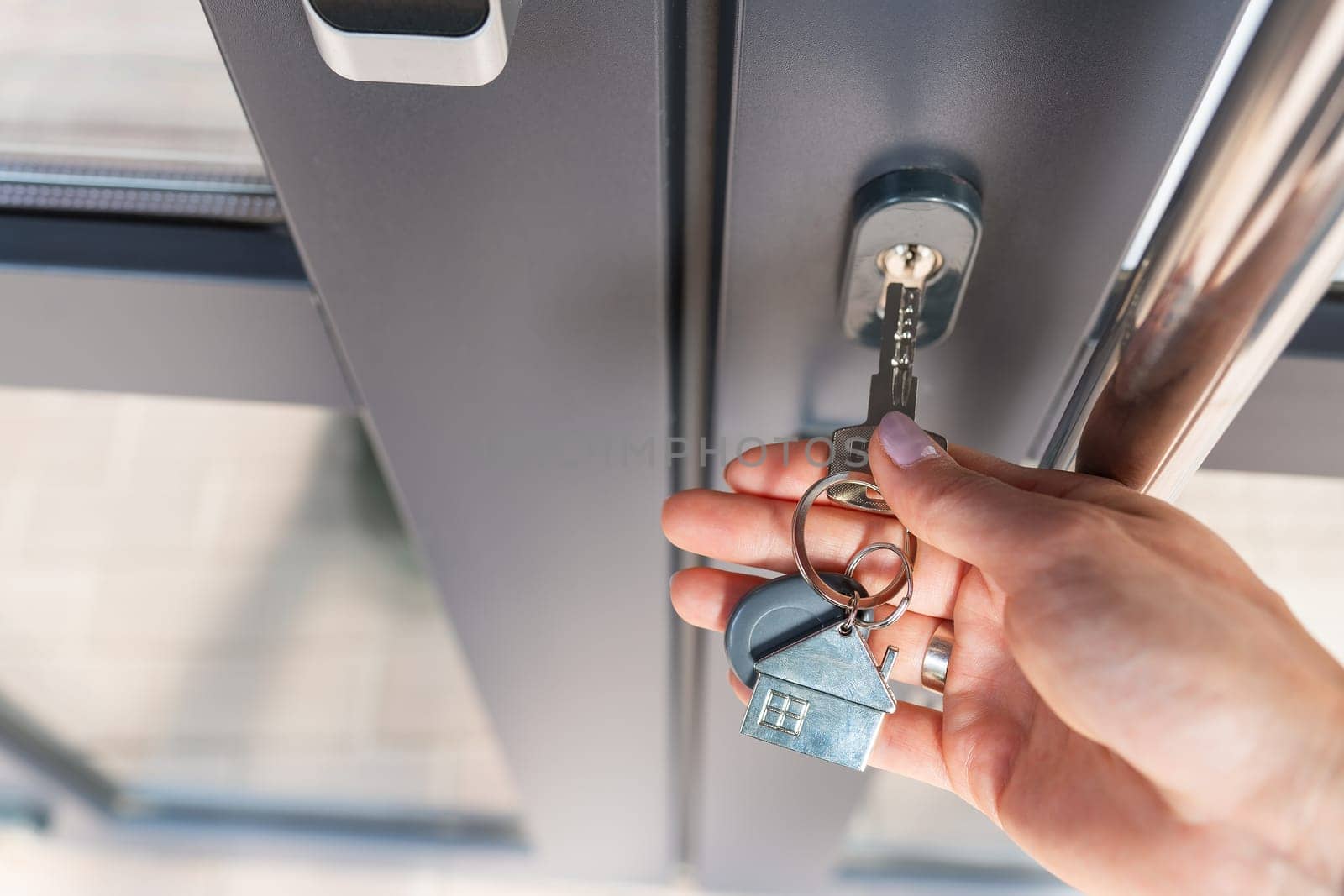 A woman's hand opens the door with a key on which the keychain hangs at home