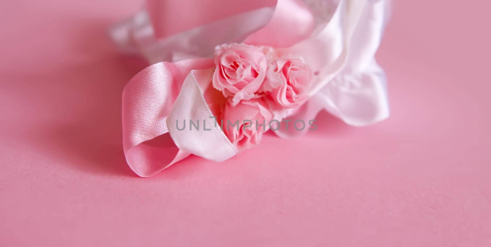 The bride's garter on a pink background. Wedding dress detail.