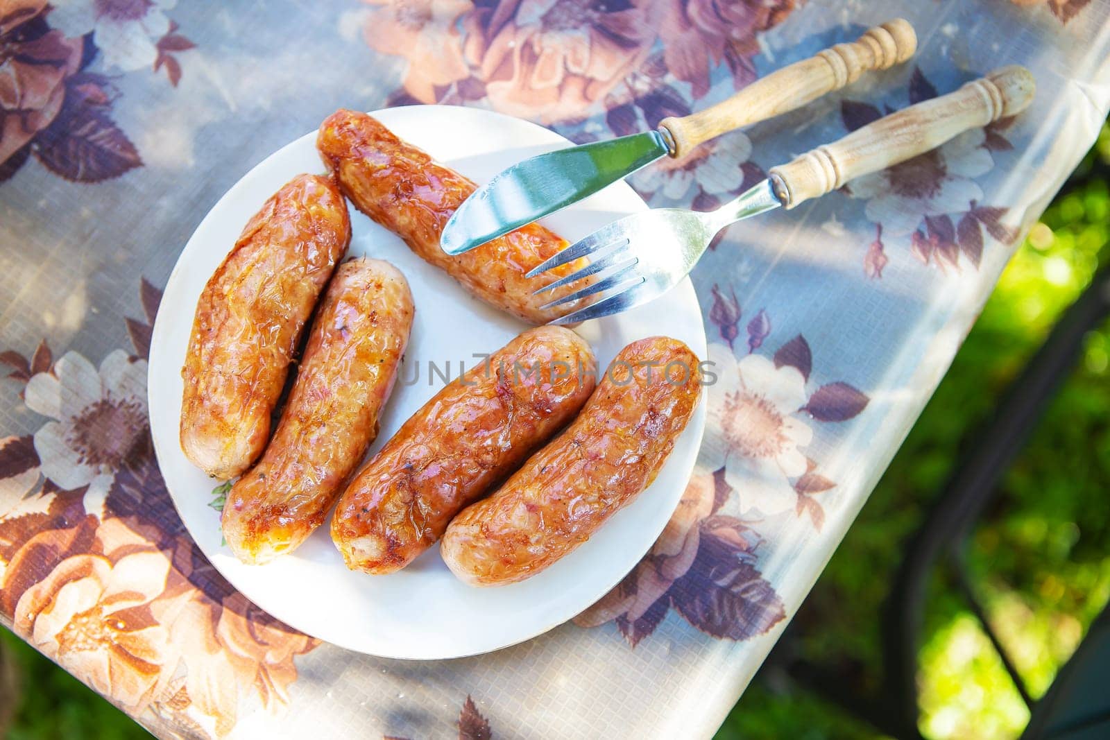 Grilled Bavarian sausages, delicious spit sausages. Shish kebab with sausages on a plate. Outdoor recreation. by sfinks